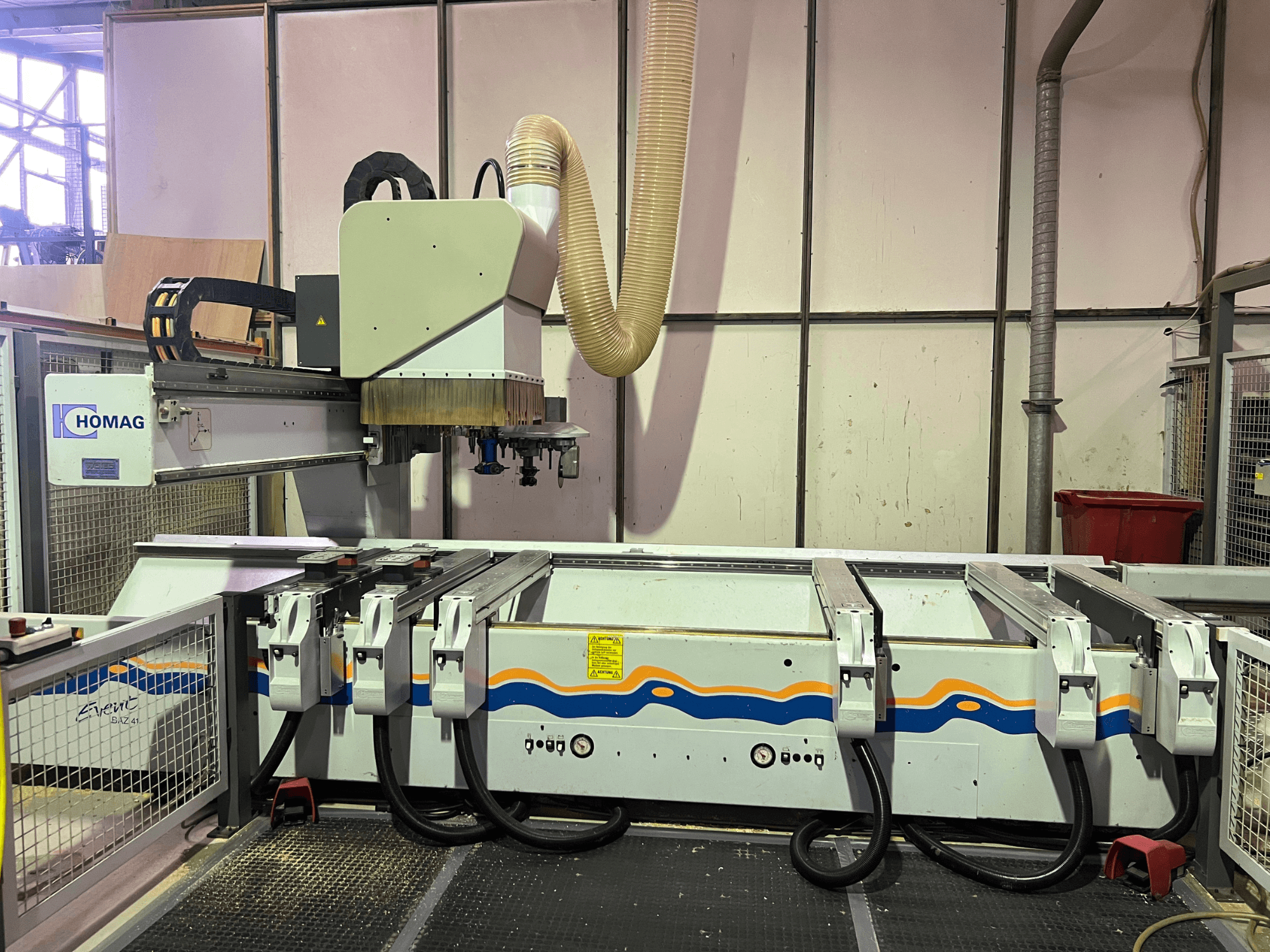 Станок с ЧПУ HOMAG BIZ 4 в мастерской; вид спереди, демонстрирующий систему пылеудаления и панель управления с кабелями.