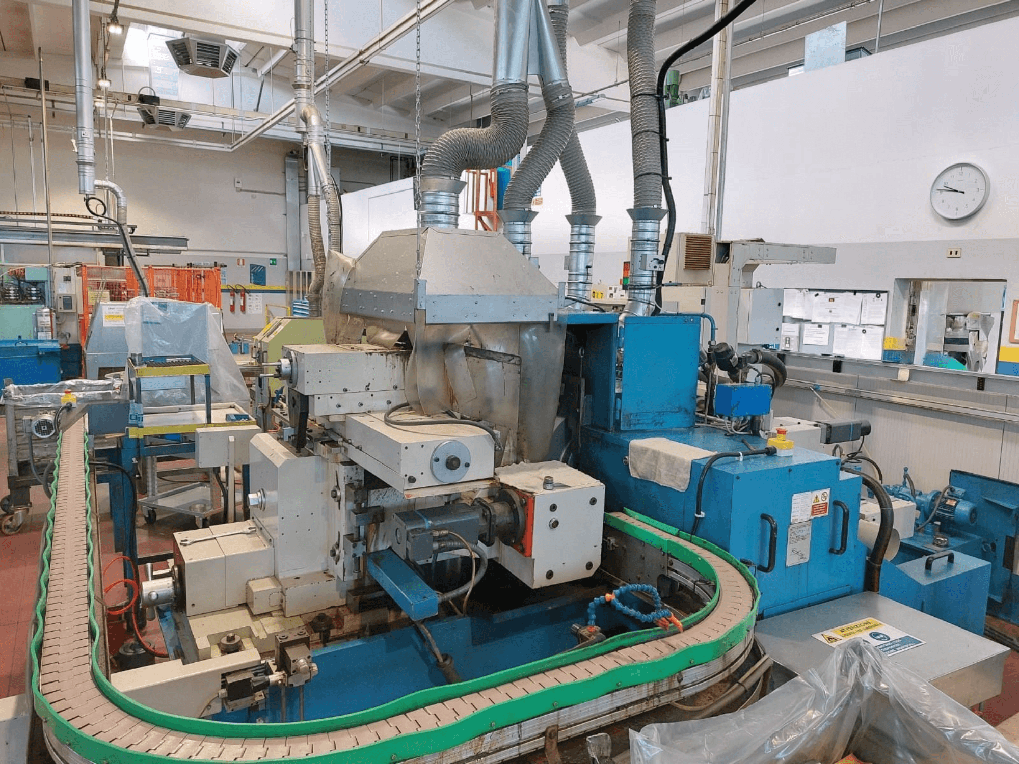 Бесцентрово-шлифовальный станок GHIRINGHELLI M300SP610 CNC3A, вид спереди, демонстрирует сложные механизмы и детали конвейера.
