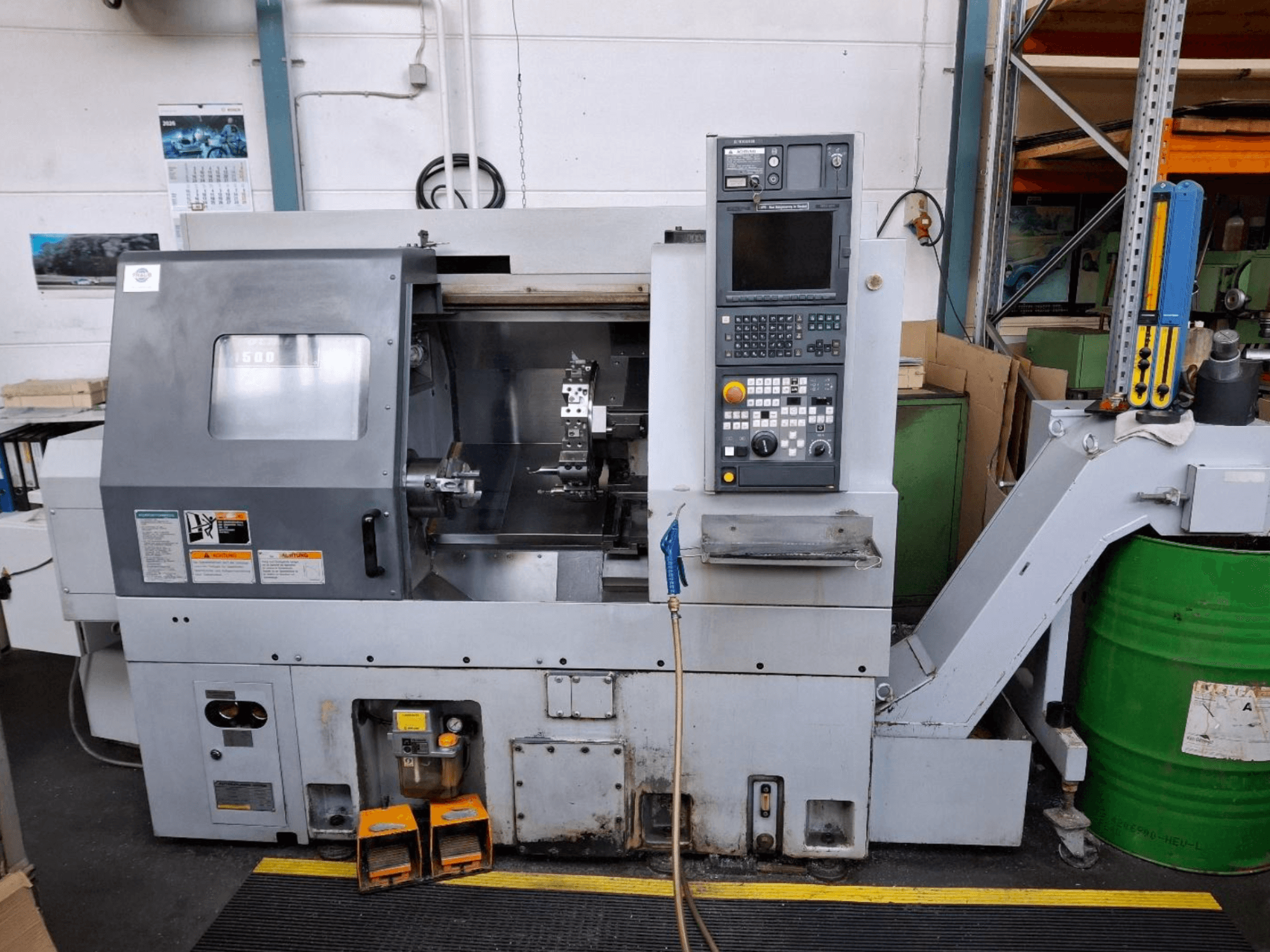 Горизонтальный токарный станок MORI SEIKI CL 1500 T, вид спереди с панелью управления, видимыми инструментами и индикатором работы.