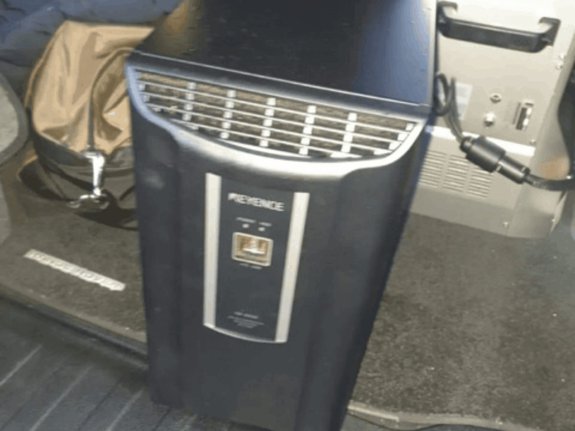 Система автоматизации KEYENCE IM-8030 на переднем плане, с изображением панели управления и вентиляционных отверстий, на фоне салона автомобиля.