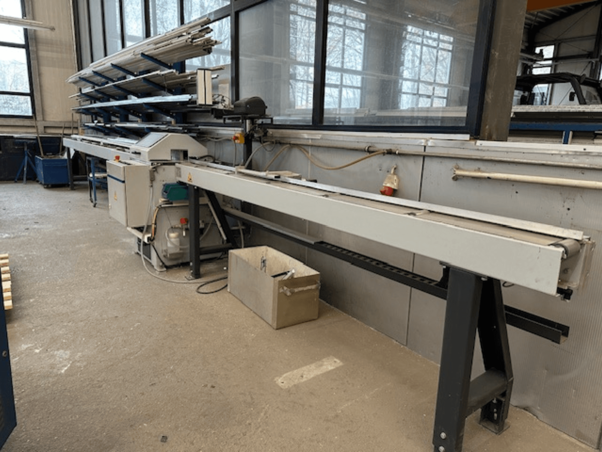 Циркулярная пила по металлу SCHÜCO PGS в мастерской, вид сбоку с регулируемой режущей станиной и полкой для металлических профилей вверху.