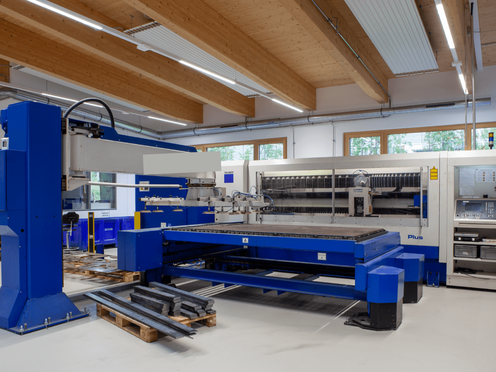 Лазерный резак TRUMPF TRUMATIC L 2530 Plus с CO₂-лазером в цехе, отличающийся большим режущим столом и промышленным дизайном.