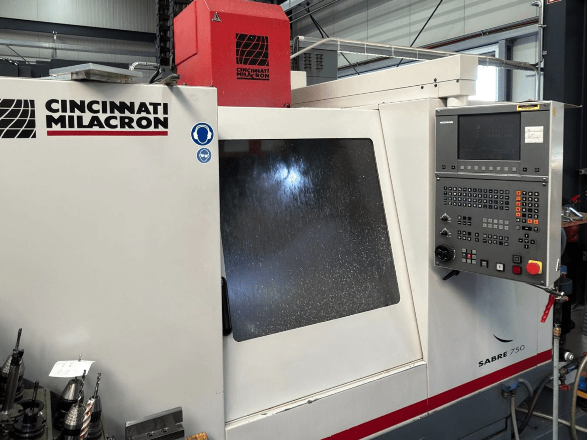 Вертикальный обрабатывающий центр Cincinnati Milacron Sabre 750, вид спереди, с панелью управления и частично затененным стеклом.