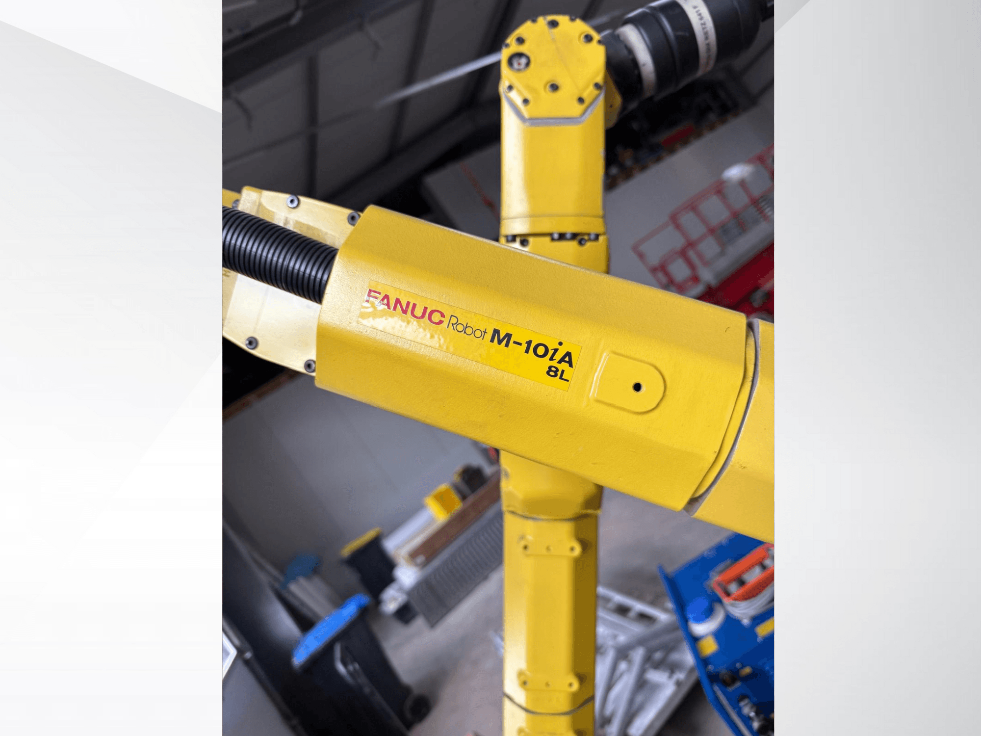 Робот FANUC M-10iA 8L желтого цвета, вид сбоку, демонстрирует шарнир руки и механические компоненты в промышленной обстановке.