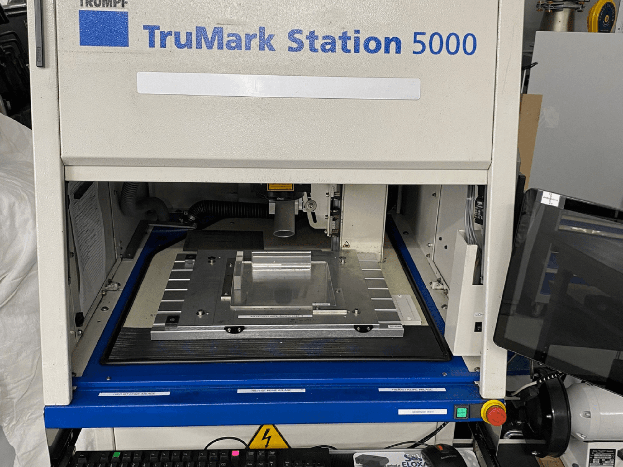 Вид спереди лазерного маркировочного станка TruMark Station 5000 демонстрирует рабочий стол, органы управления и экран мониторинга.