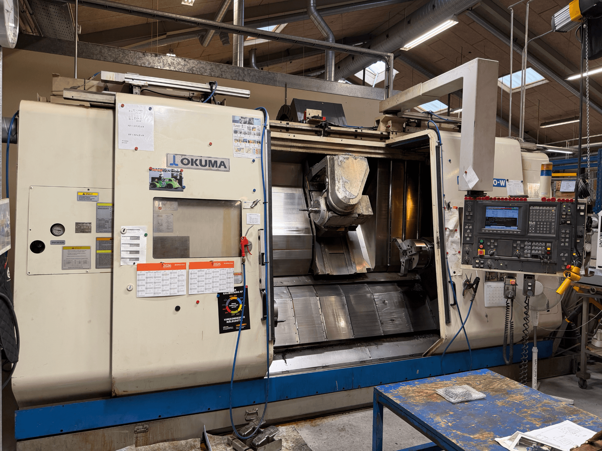 Токарно-фрезерный центр Okuma MacTurn350-W, вид спереди, демонстрирующий панель управления и свободный доступ к зоне обработки.