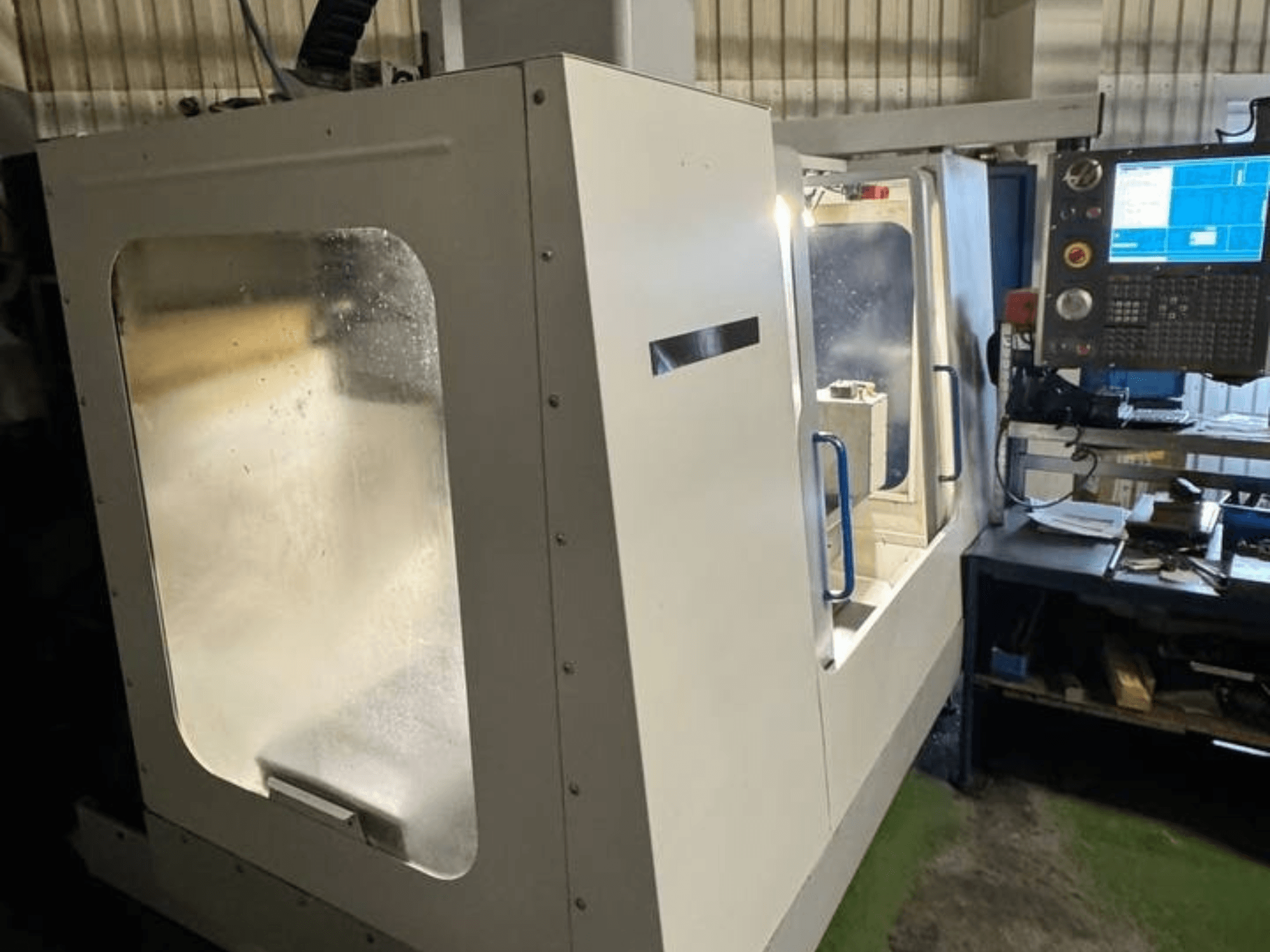 Вертикальный обрабатывающий центр HAAS VCE 750 с видом сбоку, с панелью управления и прозрачным защитным кожухом.