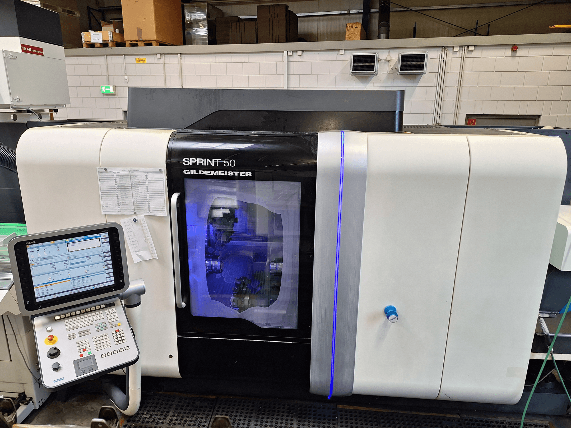 Горизонтальный токарный станок DMG Sprint 50 2T, вид спереди, с панелью управления и прозрачным кожухом, демонстрирующим механизмы внутри.