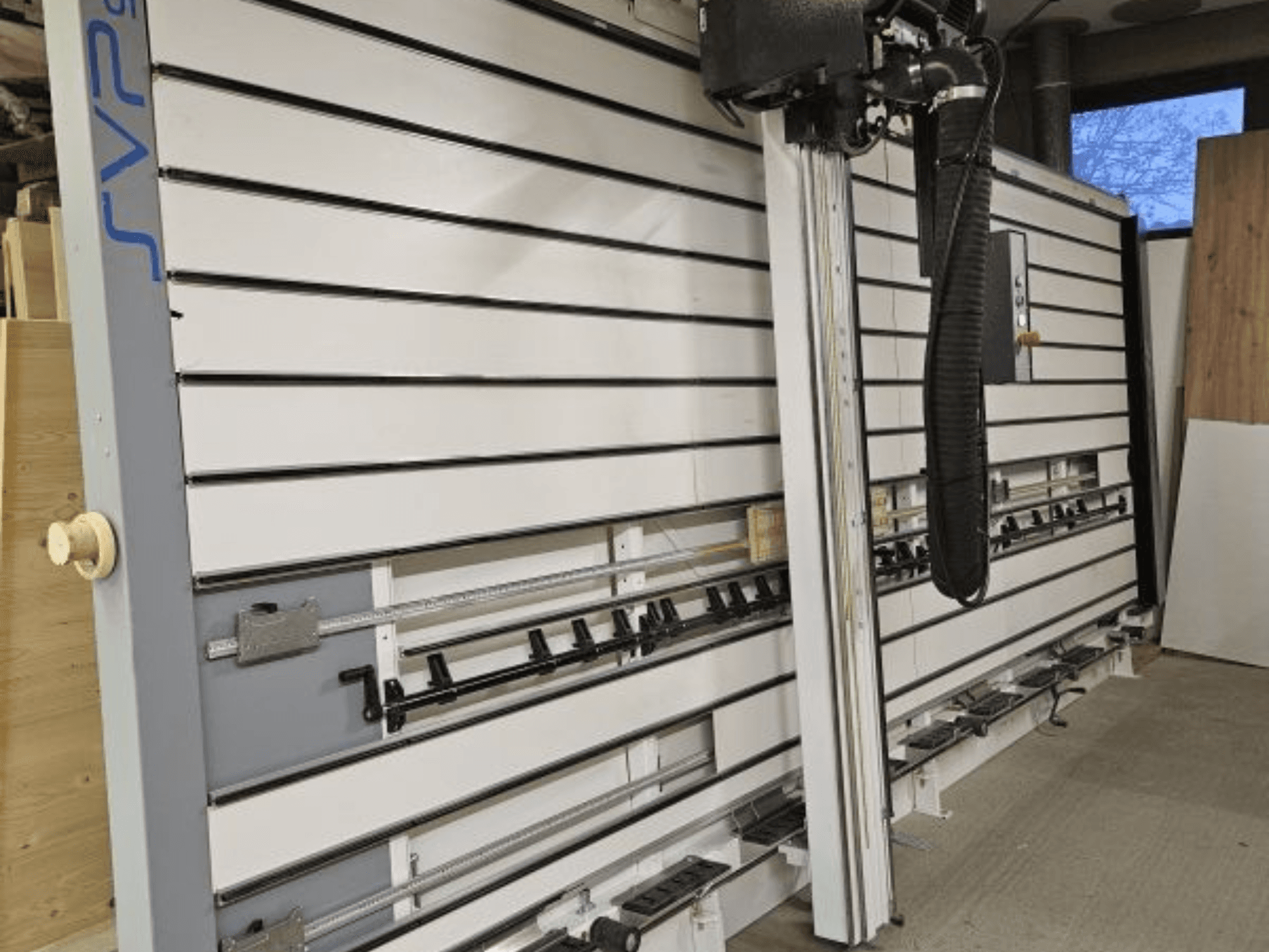 Раздвижная пила SVP в мастерской, вид спереди, с регулируемыми направляющими и подвесной системой пылеудаления.