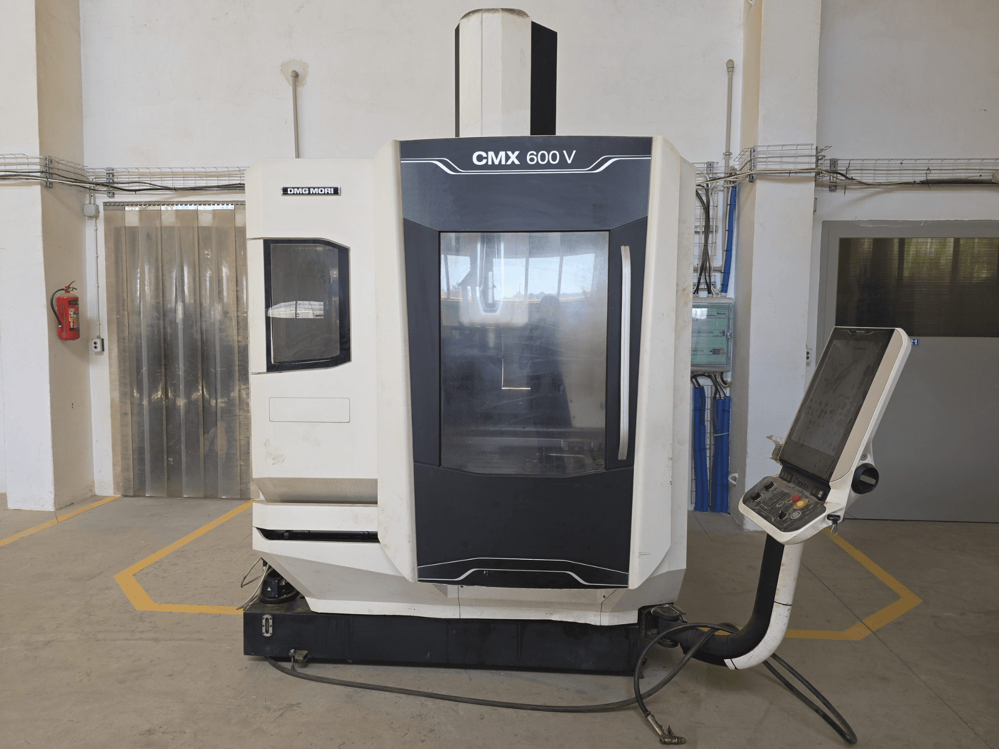 Вертикальный обрабатывающий центр DMG MORI CMX 600 V, вид спереди, демонстрирует панель управления и большое прозрачное окно.