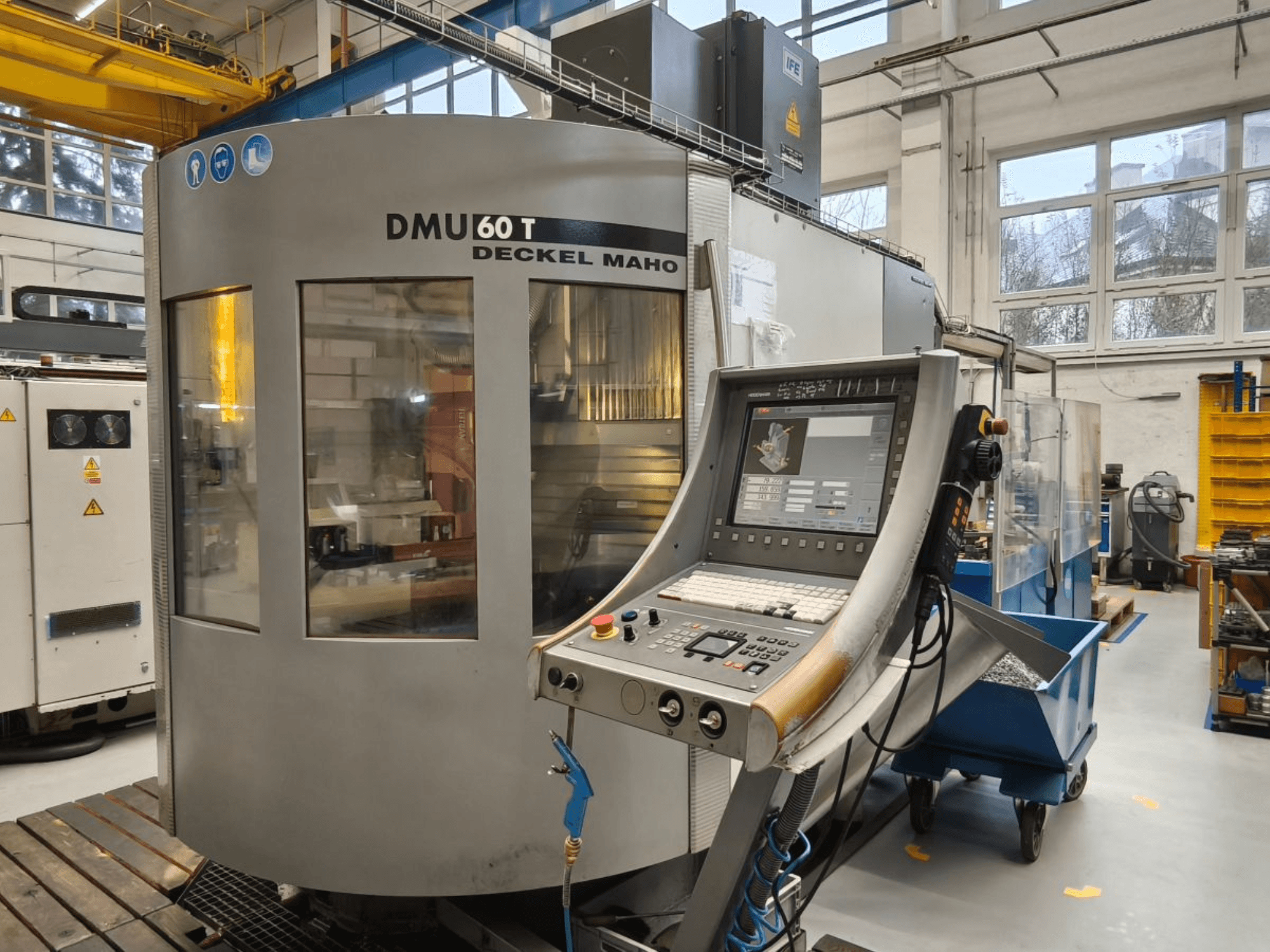 Вертикальный вид на обрабатывающий центр DECKEL MAHO DMU 60T с панелью управления, демонстрирующий прецизионные инструменты в цеху.