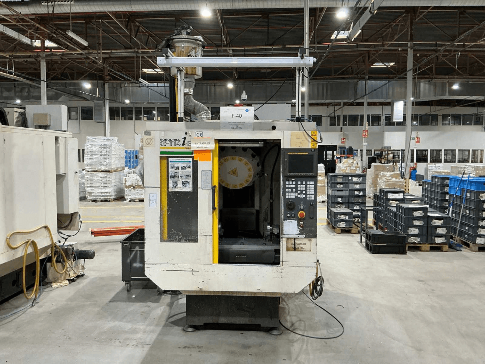 Вертикальный обрабатывающий центр FANUC ROBODRILL α-T14iB на заводе, вид спереди с панелью управления и держателем инструмента.