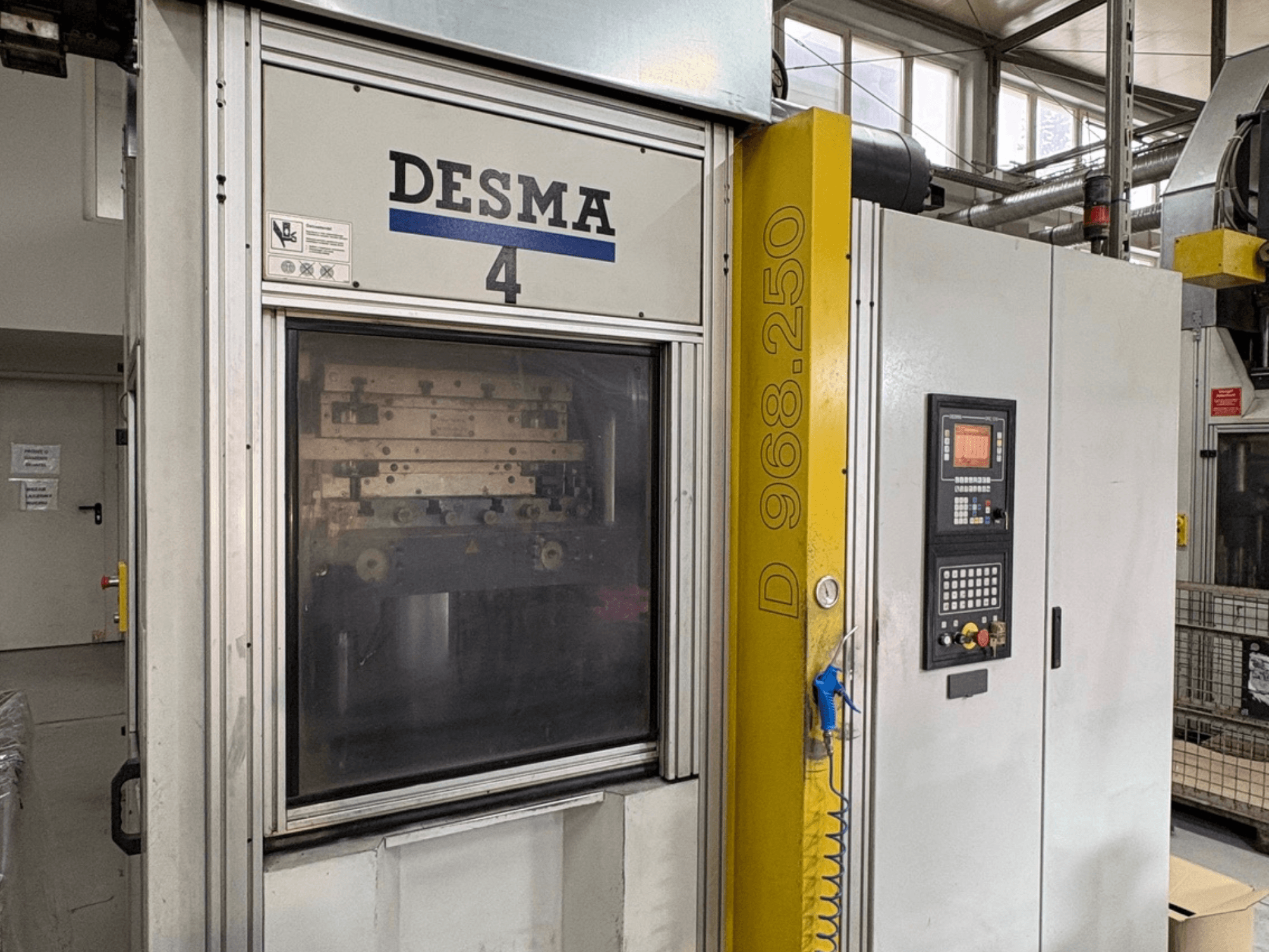 Вертикальная машина для литья под давлением Kloeckner Desma 968.250, вид спереди с панелью управления и деталями машины.