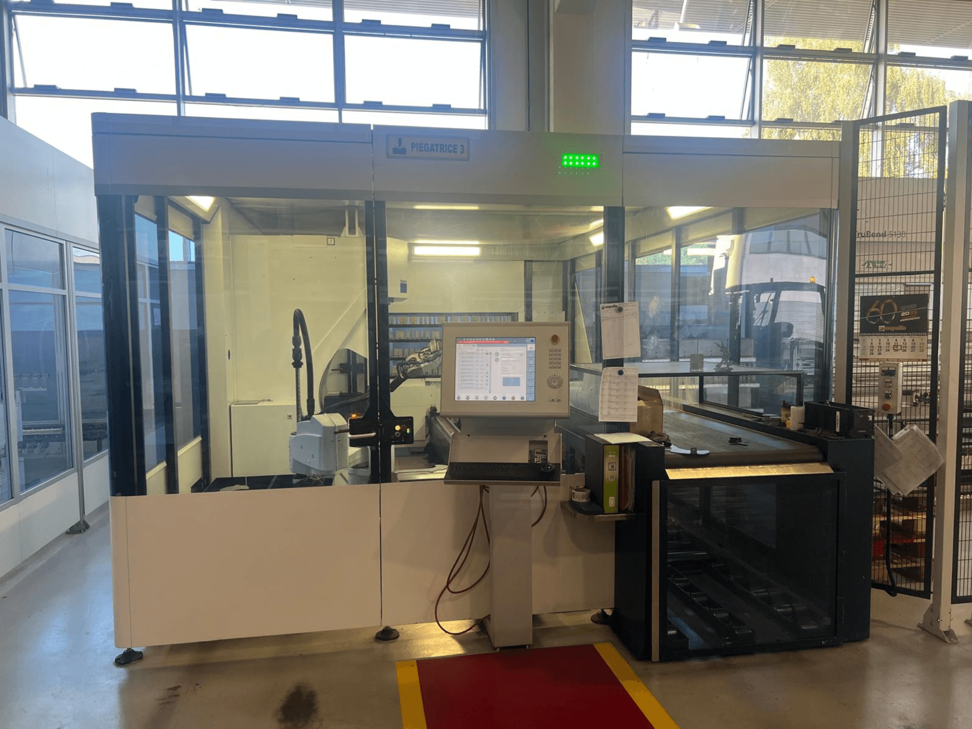 Промышленный гибочный станок, модель Piegatrice 3, вид спереди с панелью управления и роботизированной рукой, в хорошо освещенной мастерской.