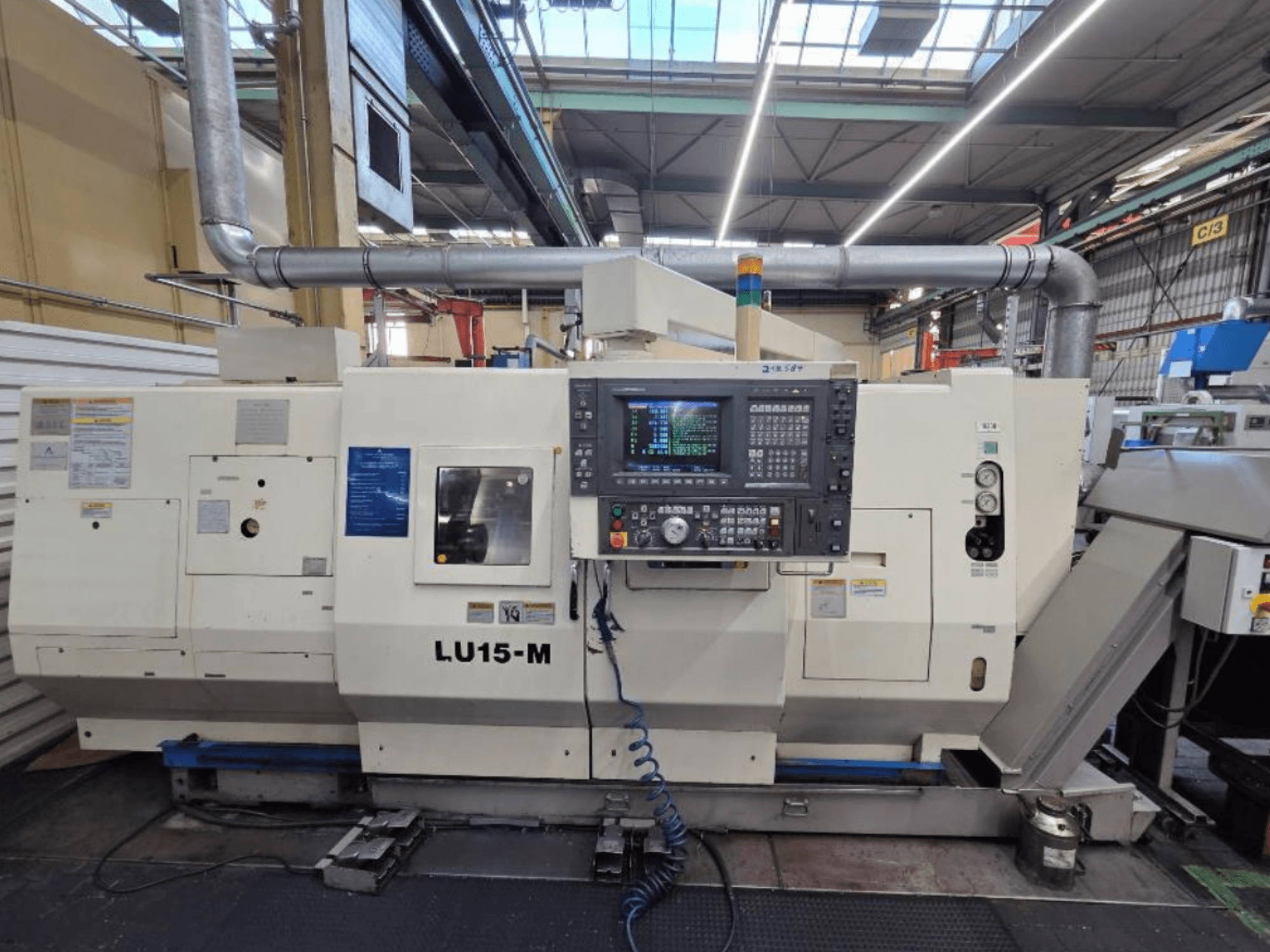 Горизонтальный токарный станок Okuma LU15 M-2SC 1000, вид спереди, показывающий панель управления и функции станка в мастерской.