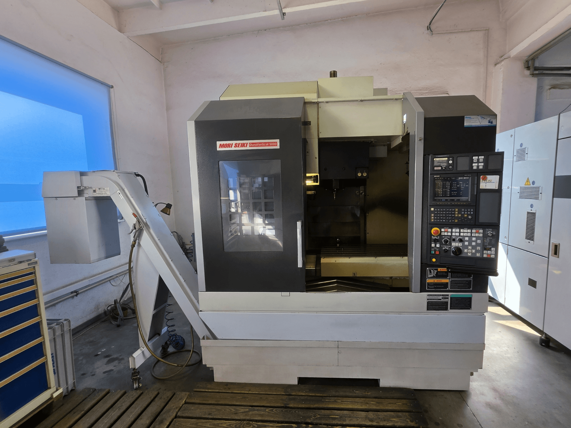 Вертикальный обрабатывающий центр MORI SEIKI DuraVertical 5080, вид спереди с панелью управления, шпинделем и держателем инструмента.