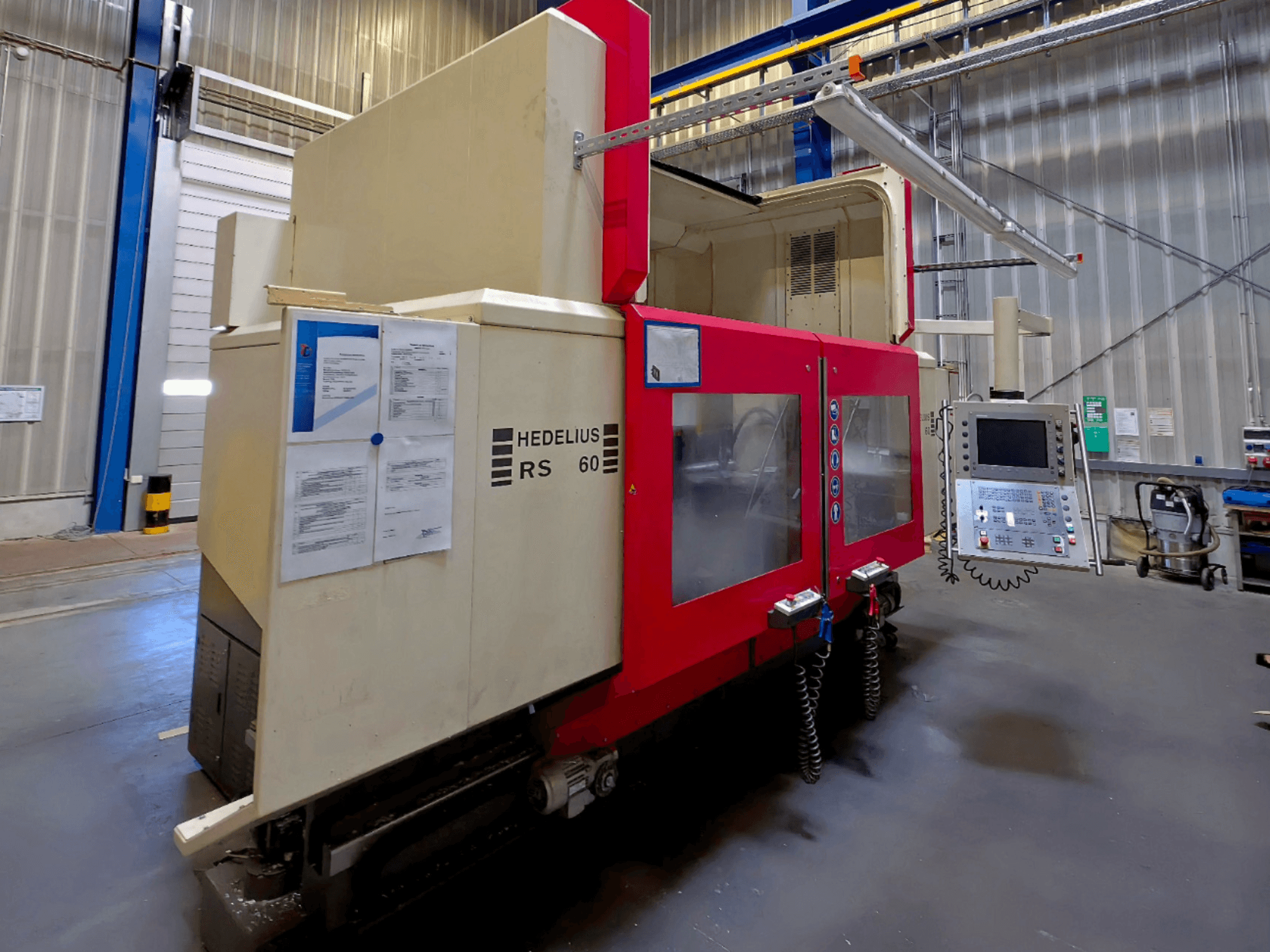 Вертикальный обрабатывающий центр HEDELIUS RS 60 K - 2000, вид сбоку, видны панель управления и инструкции по технике безопасности.