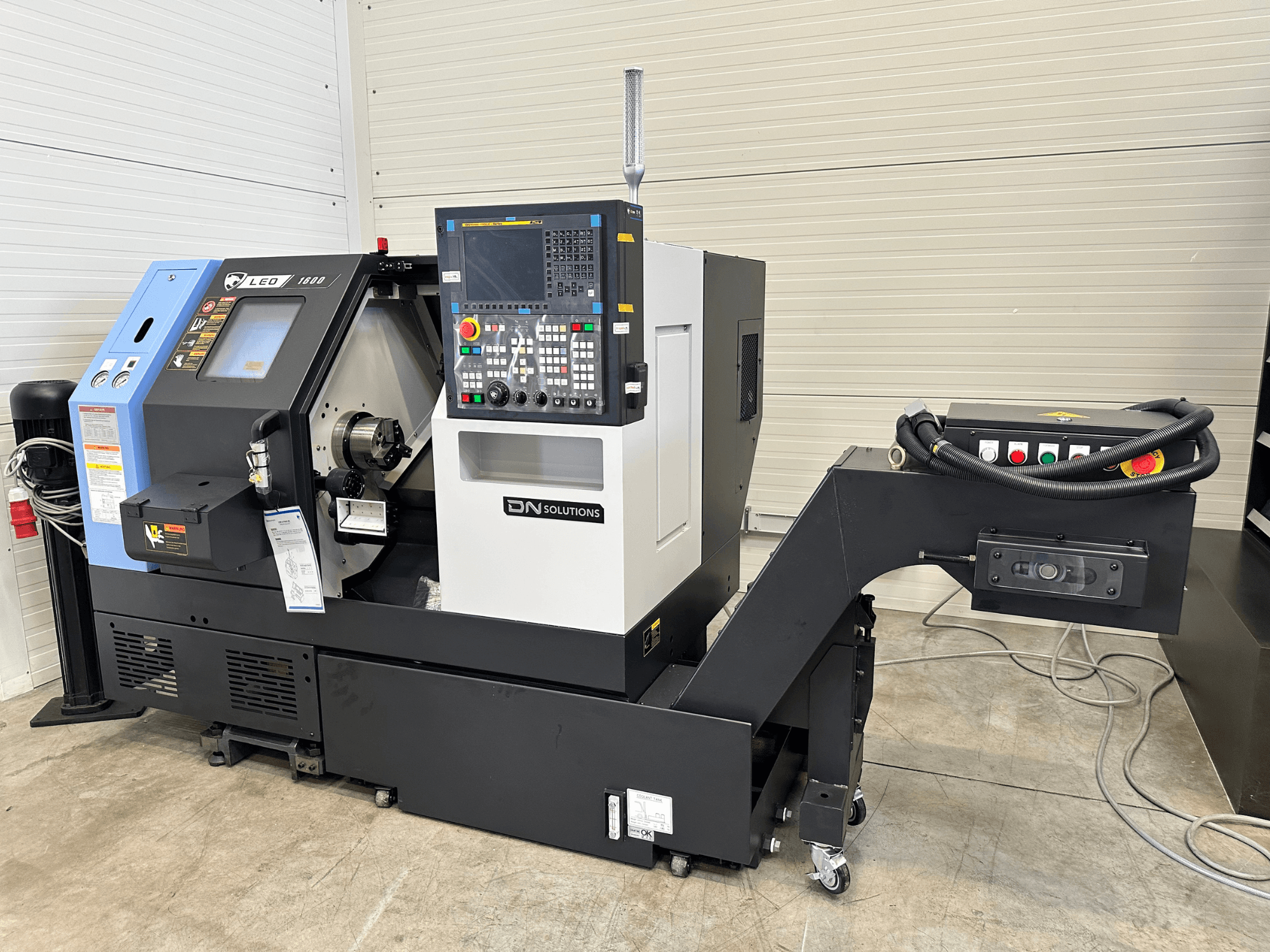 Вид спереди на токарно-фрезерный центр DN SOLUTIONS Leo 1600 с цифровой панелью управления и держателем инструментов на черном основании.