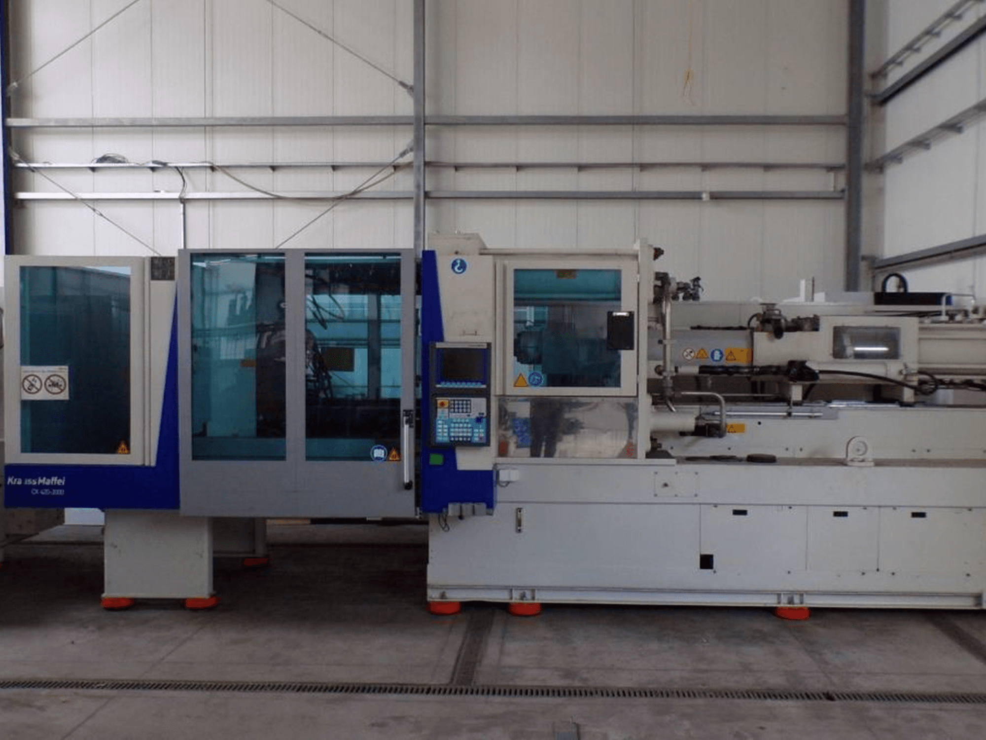 Термопластавтомат KraussMaffei, вид сбоку, панель управления и индикаторы безопасности, видны на заводе.