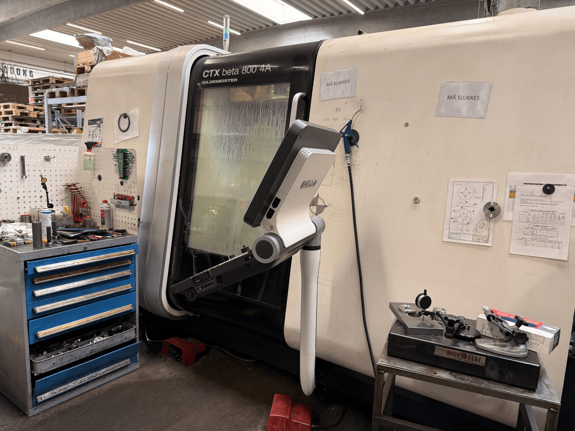 Вертикальный токарный станок DMG MORI CTX Beta 800 4a в мастерской, рядом - рычаг управления и техническая документация.