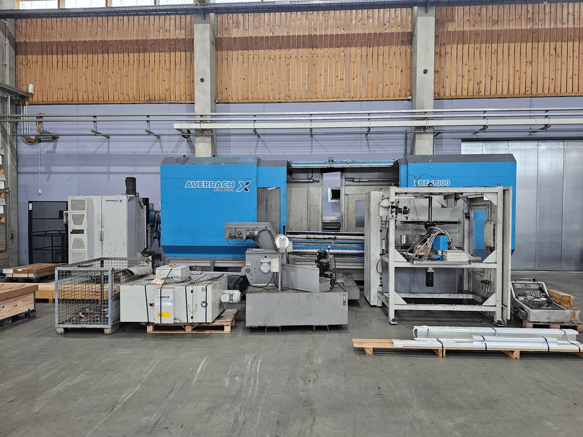 Машина Auerbach X LBF-3000 в заводских условиях, вид сбоку, серо-голубые компоненты с видимой панелью управления.