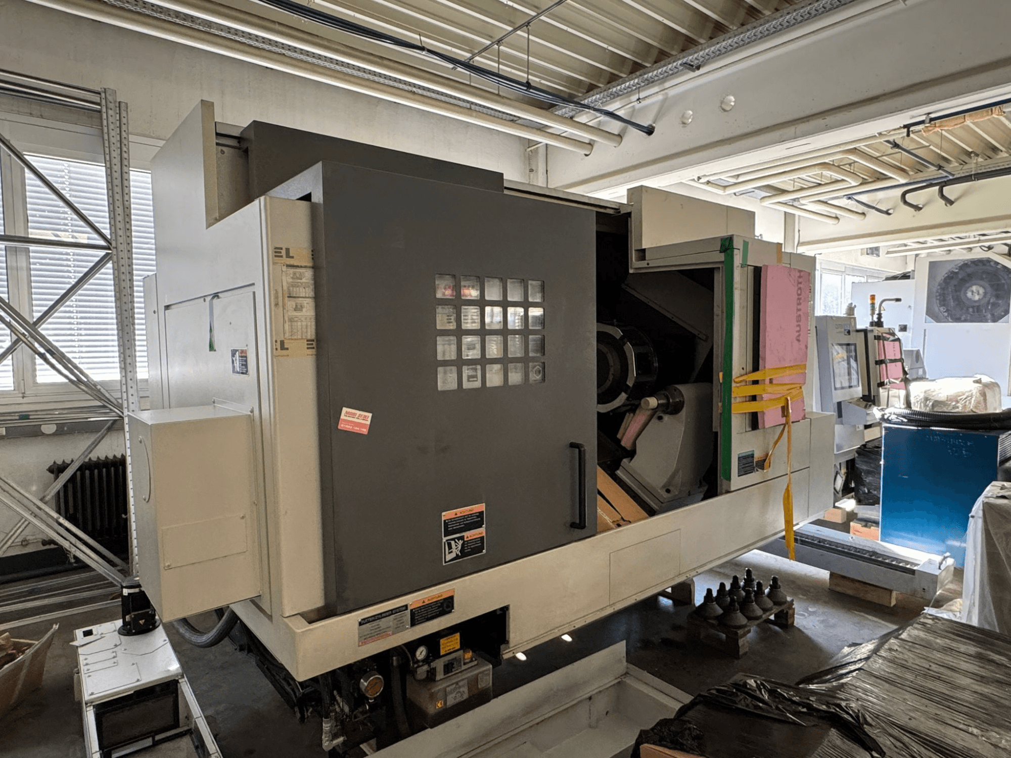 Горизонтальный токарный станок MORI SEIKI NL 3000 MC/700, вид спереди с панелью управления, зоной хранения и защитной пленкой.