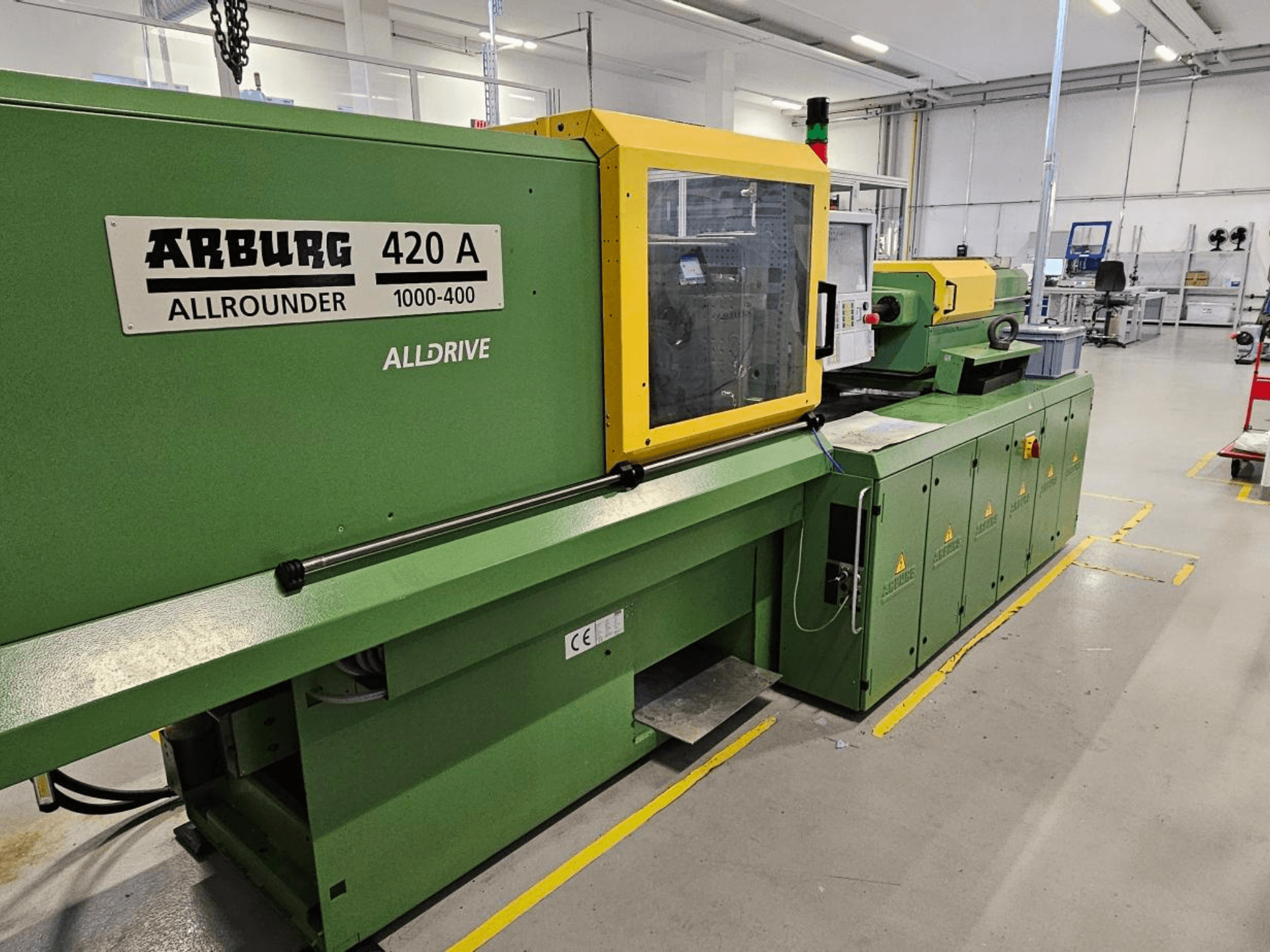 ARBURG 420 A Allrounder 1000-400, вид спереди; зеленая машина с желтой панелью, сенсорным экраном и функциями безопасности.