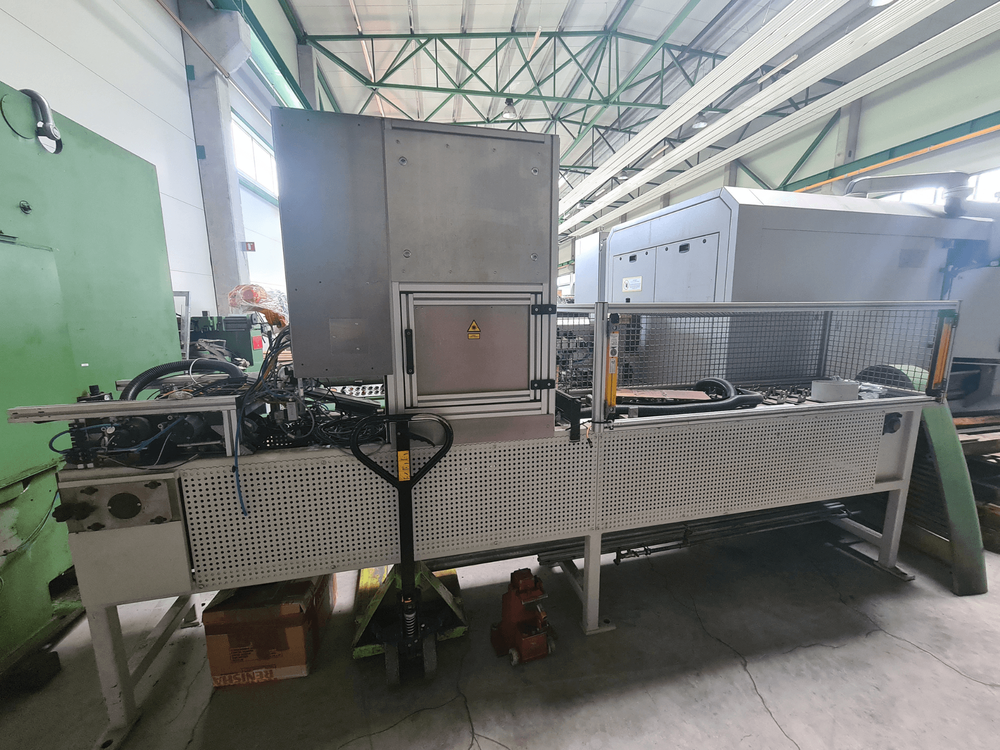 Промышленное оборудование с металлической рамой, шлангами и панелью управления, вид сбоку на заводе.