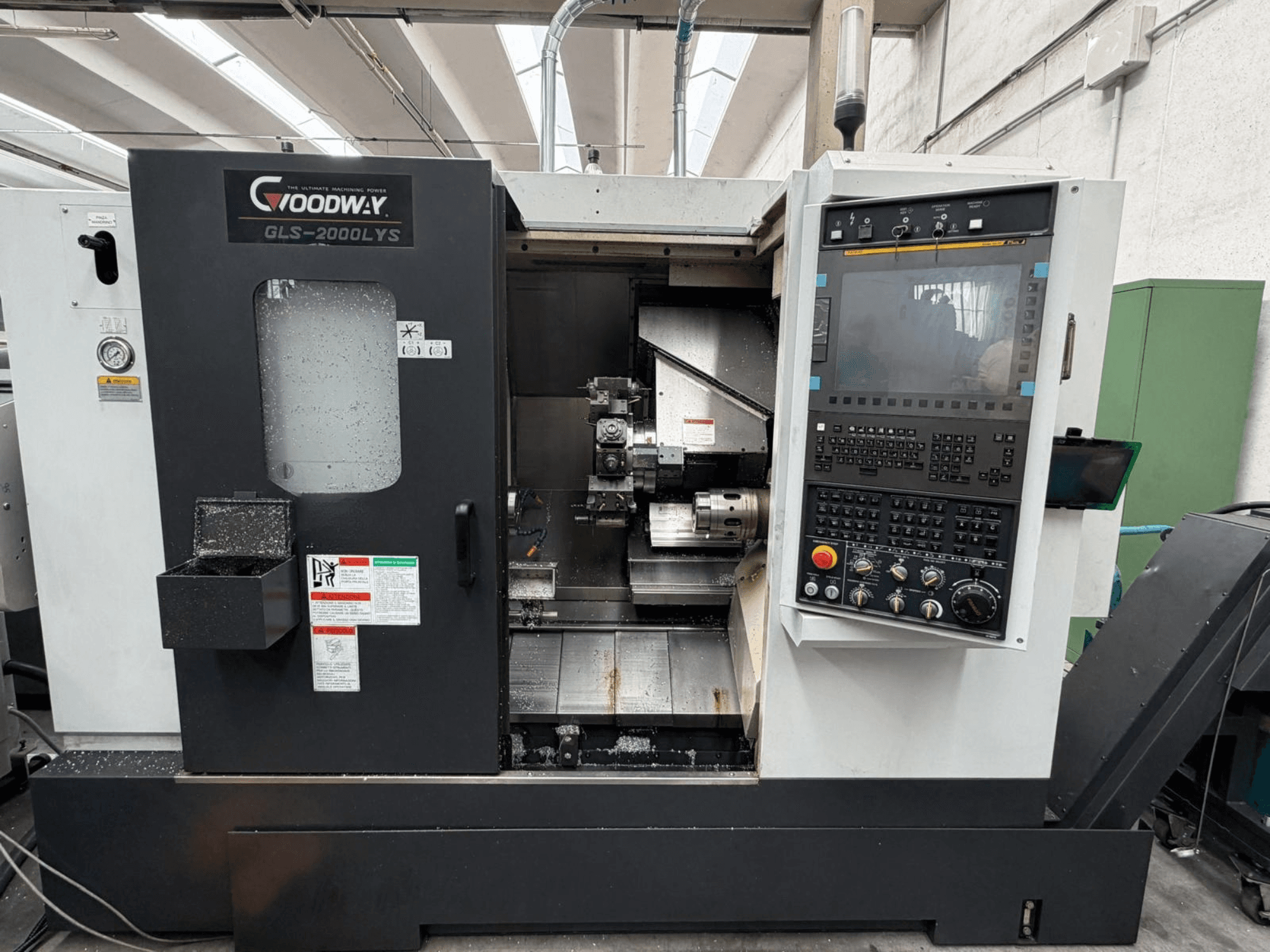 Горизонтальный токарный станок Goodway GLS-2000LYS, вид спереди, с панелью управления и видными металлическими стружками.