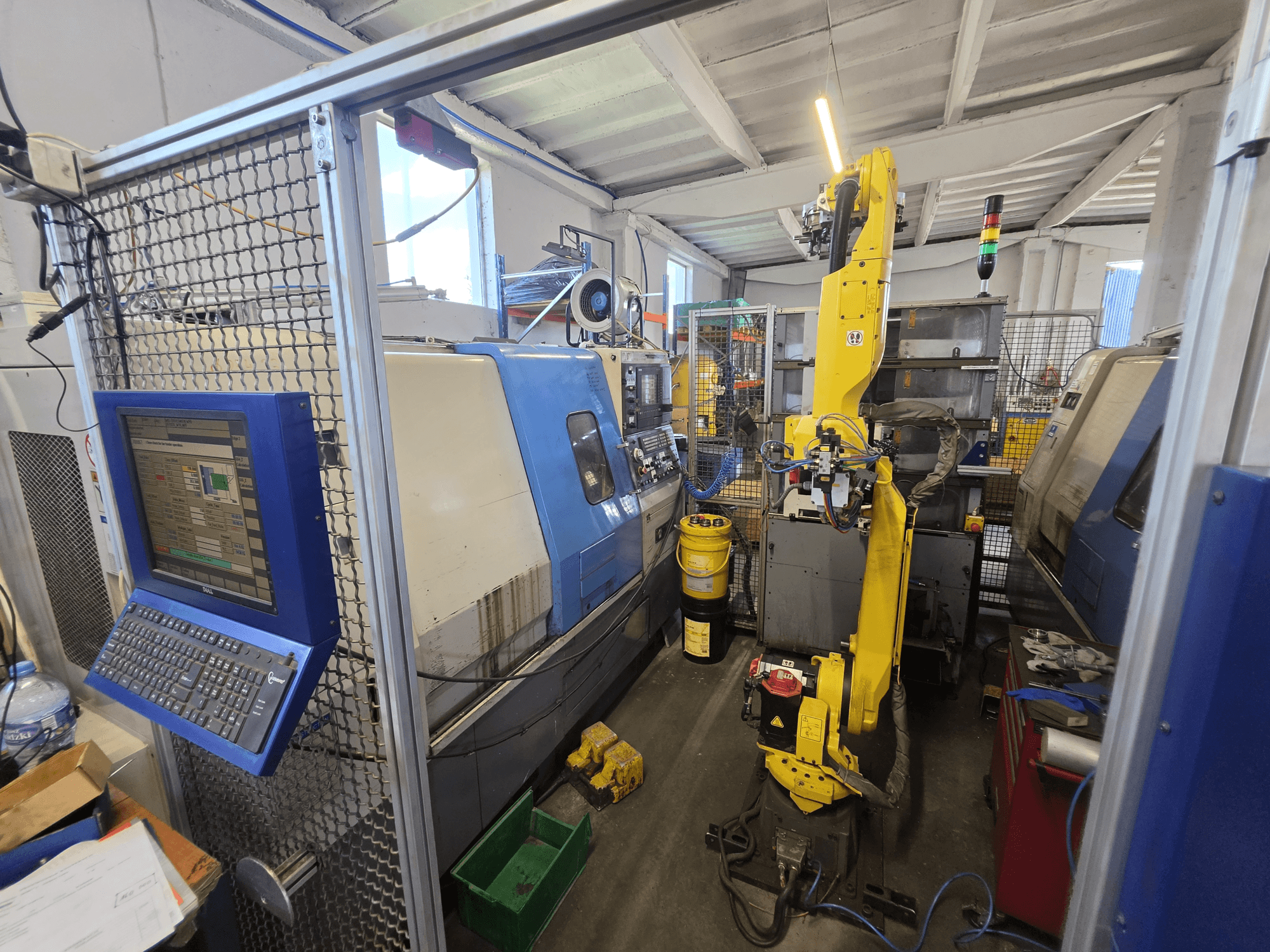 Горизонтальный токарный станок Hyundai HIT-200C с роботом FANUC M-20iA, вид спереди, на котором видны интерфейс управления и конфигурация оборудования.