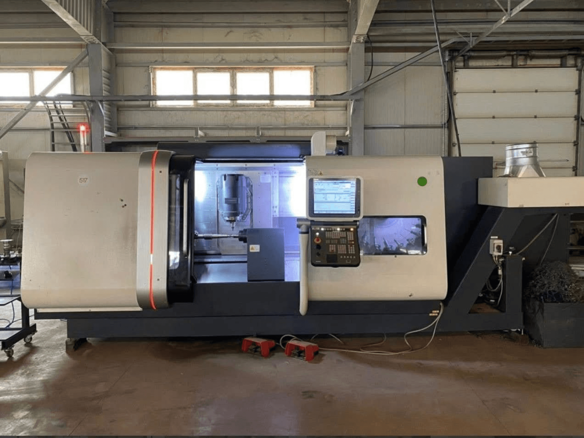 Токарно-фрезерный центр DMG MORI Beta 1250 TC, вид спереди с панелью управления, освещенной рабочей зоной и видимыми режущими инструментами.