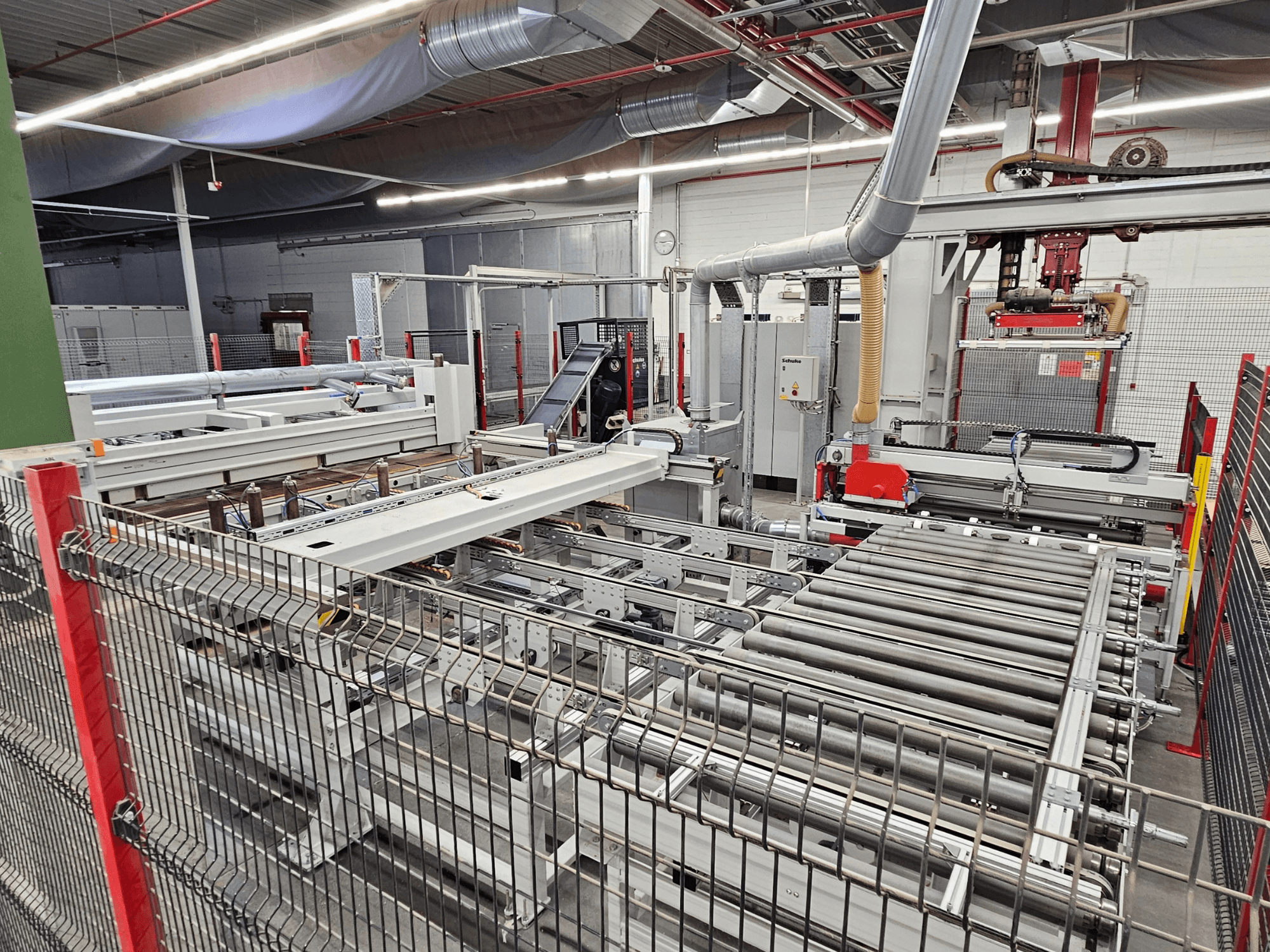 Панельная пила HOLZMA HPP81-3200, вид спереди, с роликами конвейера и компонентами оборудования в мастерской.