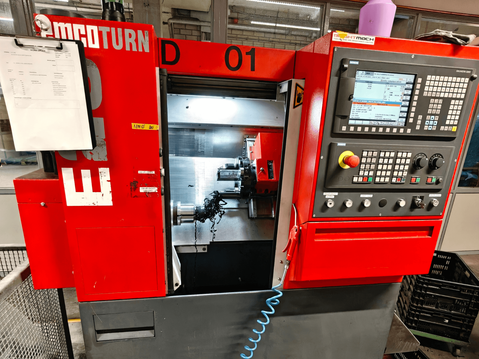 Вид спереди горизонтального токарного станка EMCO TURN E25 с элементами управления, держателем инструмента и рабочей зоной со стружкой.