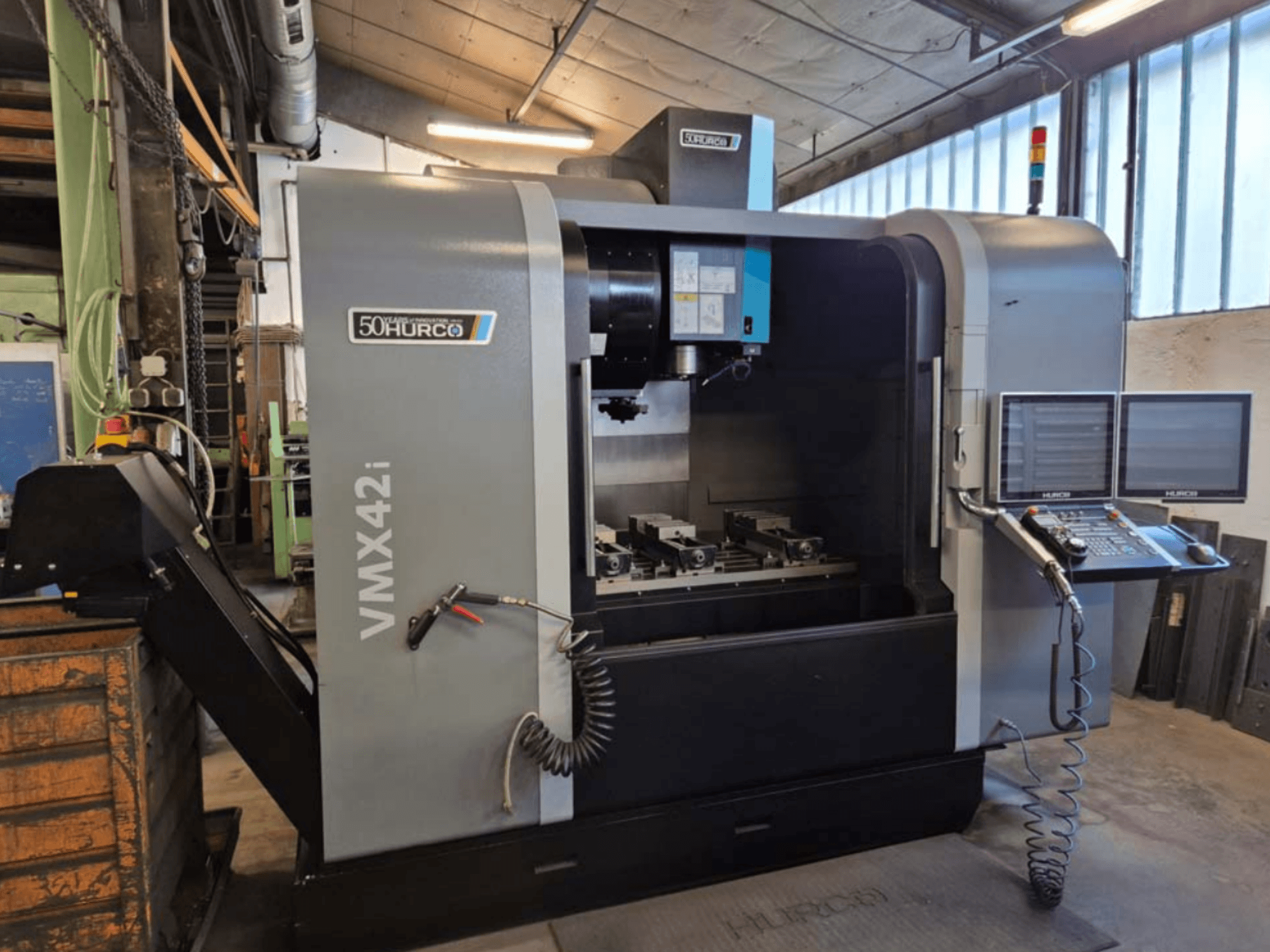 Вертикальный обрабатывающий центр Hurco VMX 42i, вид спереди, демонстрирует панель управления и рабочую зону с тисками.