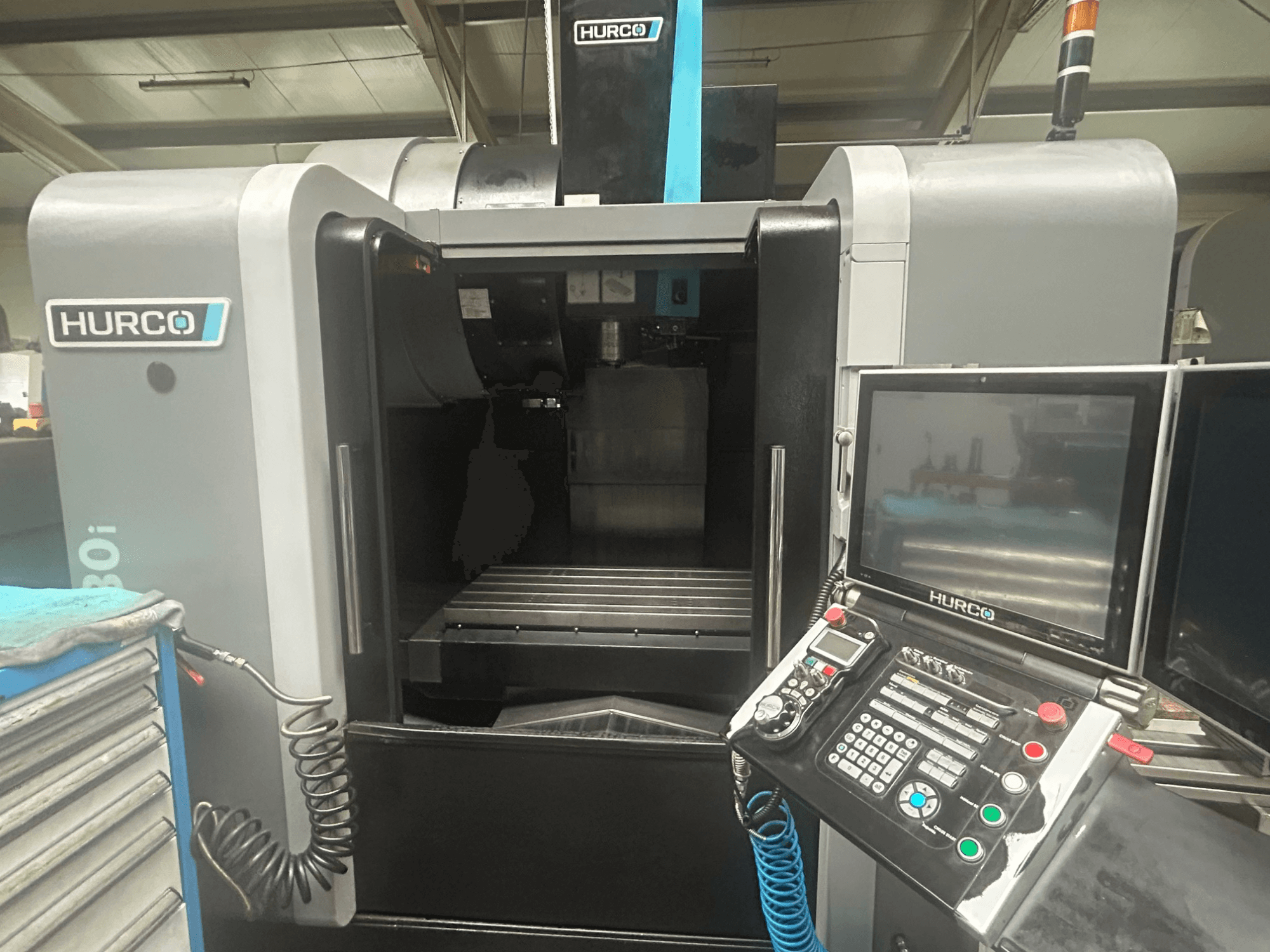 Вид спереди станка с ЧПУ Hurco VM30i, панель управления с кнопками, дисплей и место для хранения инструментов.