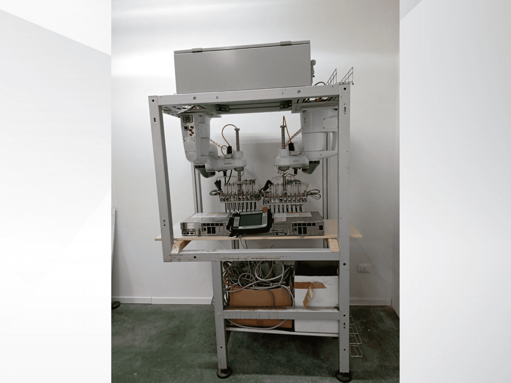 Автоматизированная роботизированная рабочая станция с двумя манипуляторами, дисплеем и электроникой на металлической раме, вид спереди, передовая технология.