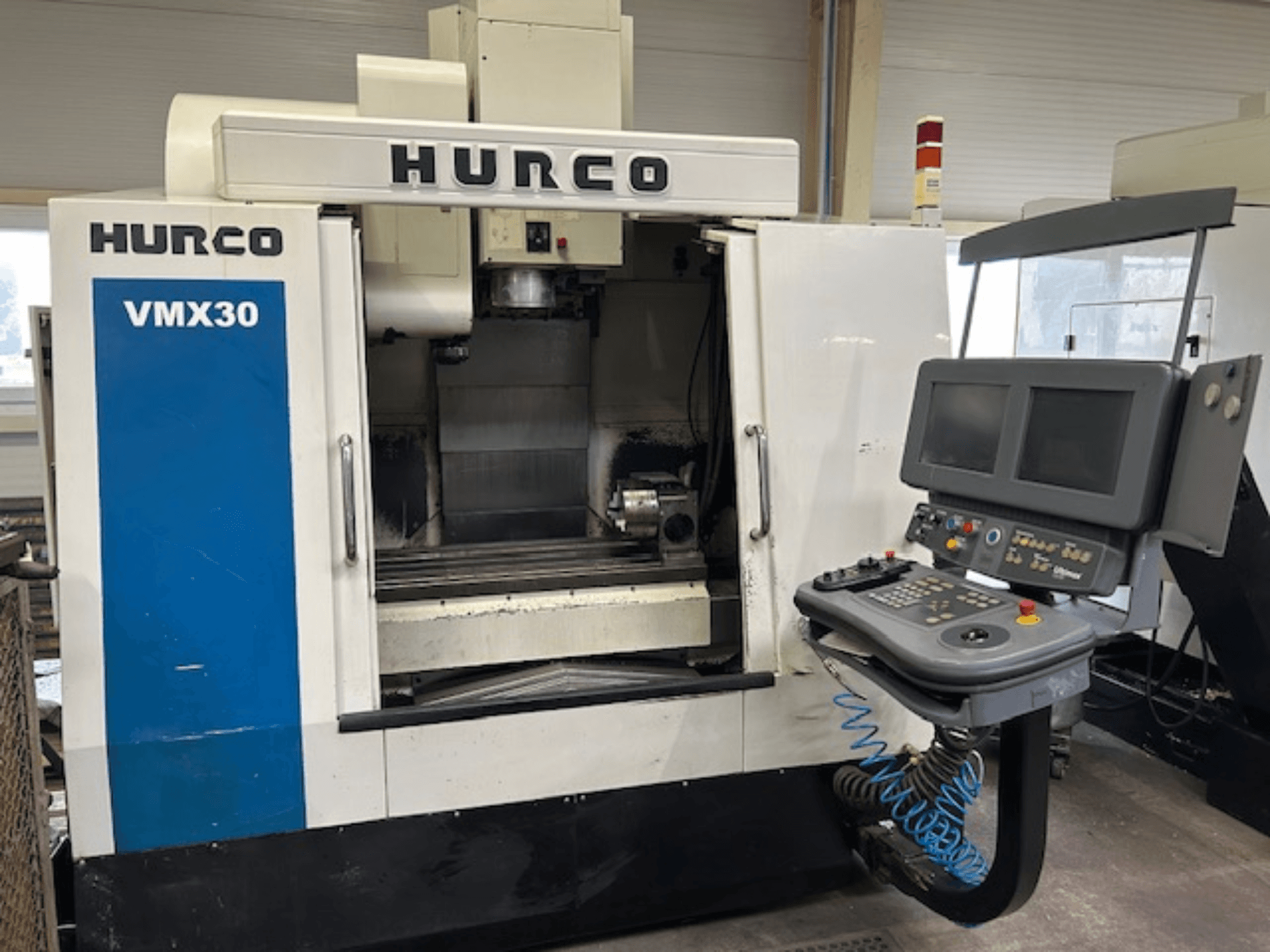 Фрезерный станок с ЧПУ Hurco VMX30 в мастерской, вид спереди; панель управления с двумя экранами и кнопками управления.