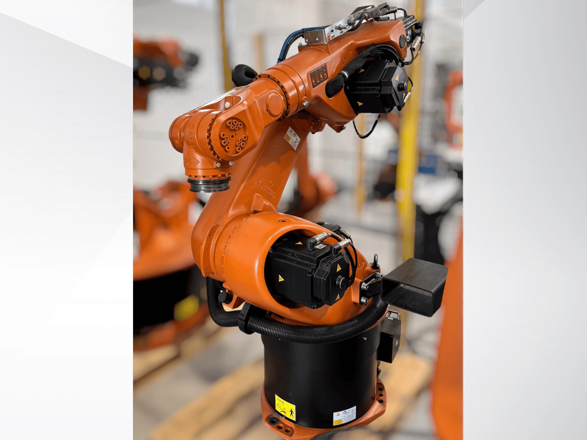 Роботизированная рука KUKA KR 60-3 оранжевого цвета; вид сбоку, показывающий основание, шарниры и модули управления для выполнения задач автоматизации.