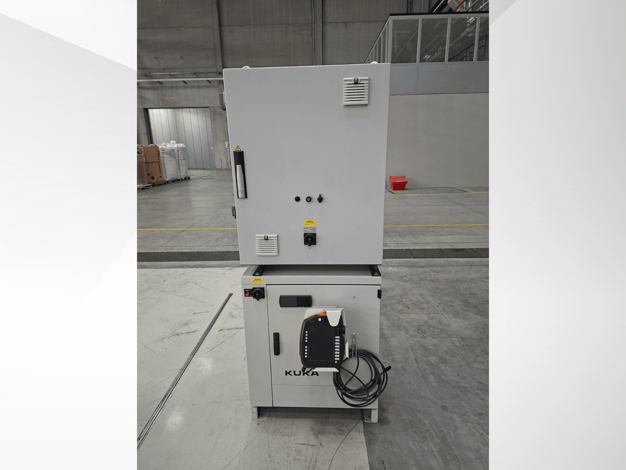 Контроллер манипулятора робота KUKA KR 90 R2700 PRO C4 FLR, вид спереди с панелью управления и предупреждающими надписями на просторном складе.