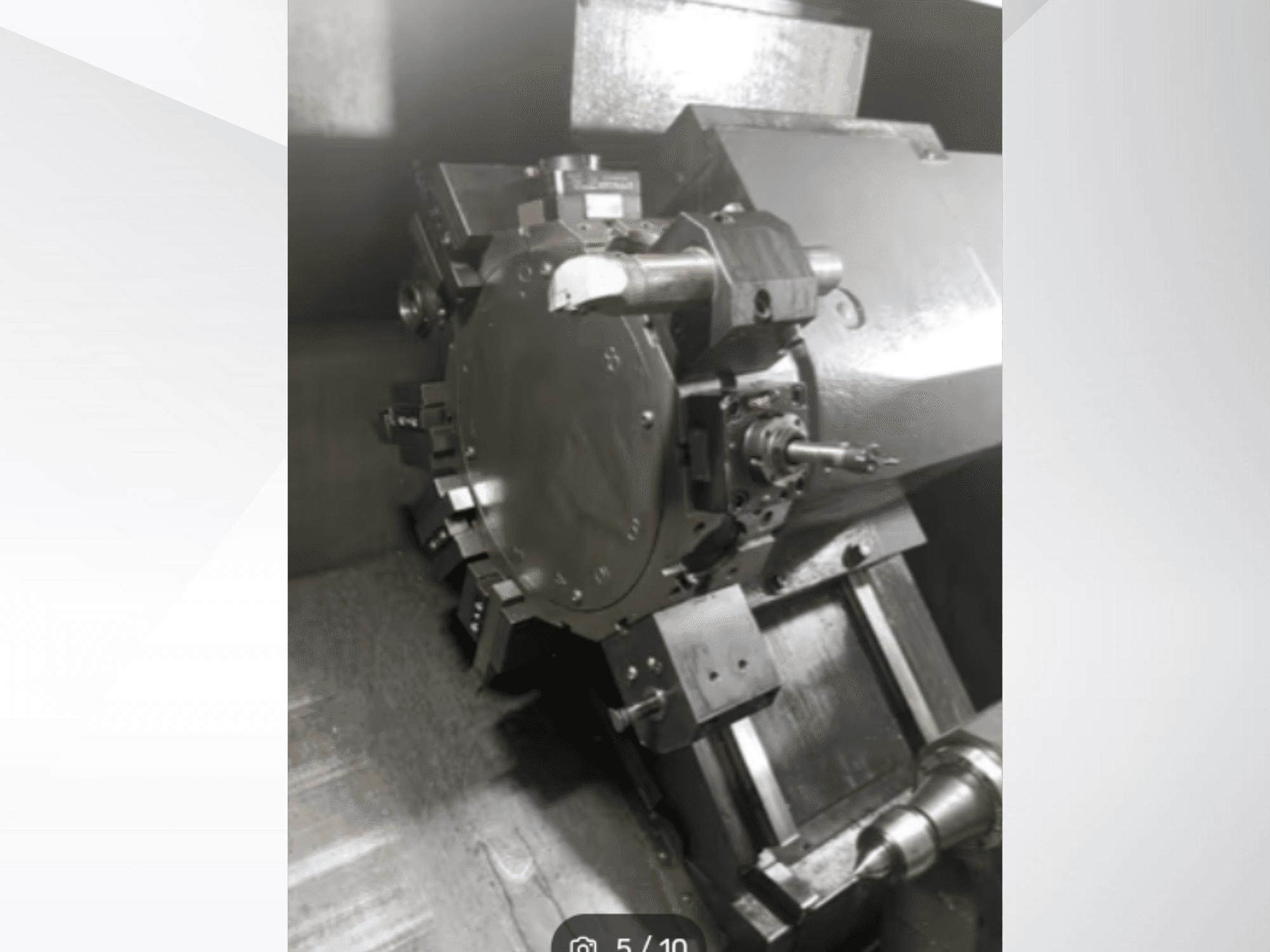 Крупный план детали прецизионного станка с изображением шестеренок и металлических деталей, снятый с углового ракурса. Бренд не виден.