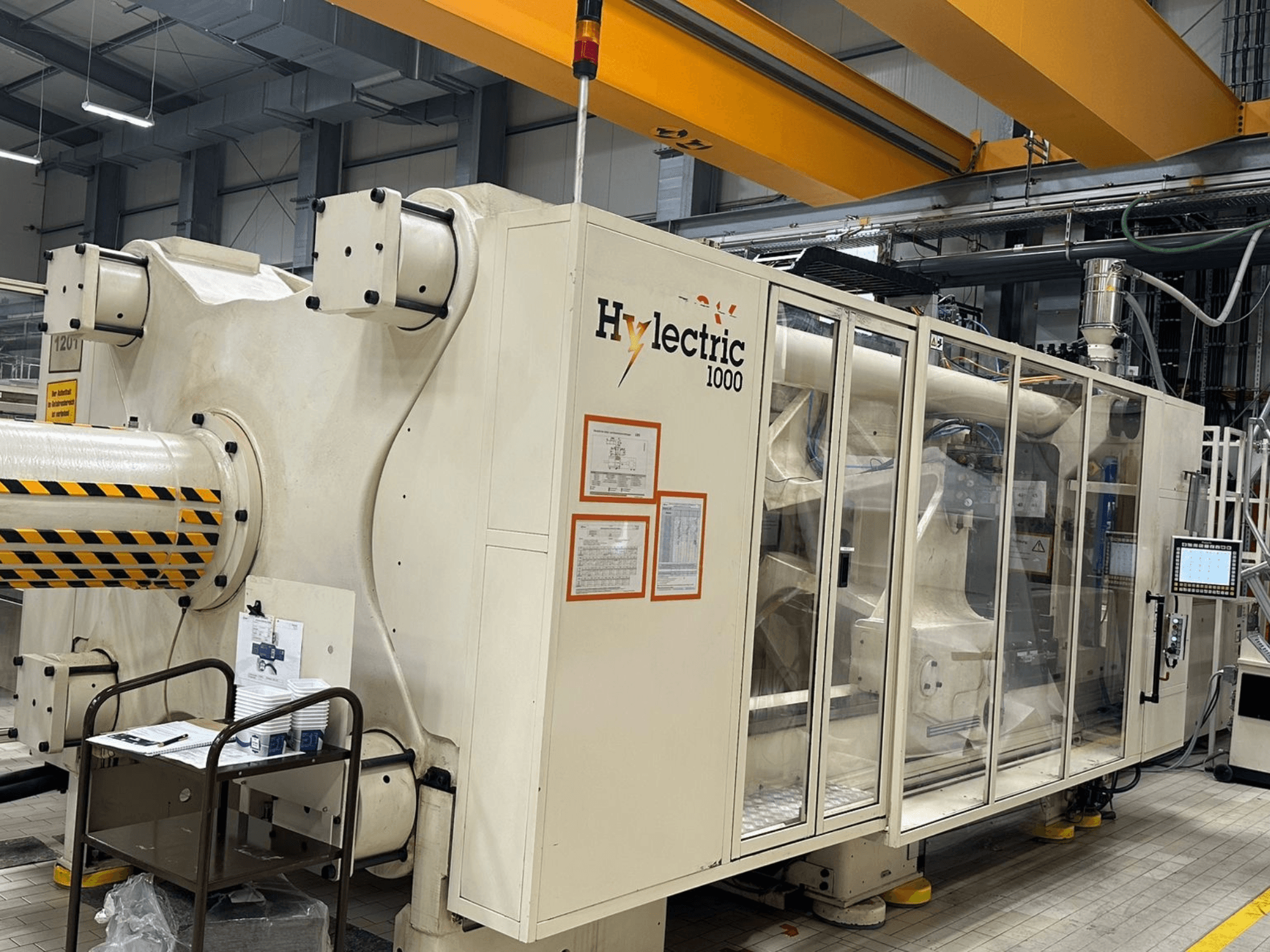 Электрическая термопластавтомат Husky Hylelectric H1000 RS95/80, вид сбоку с видимой панелью управления и средствами безопасности.