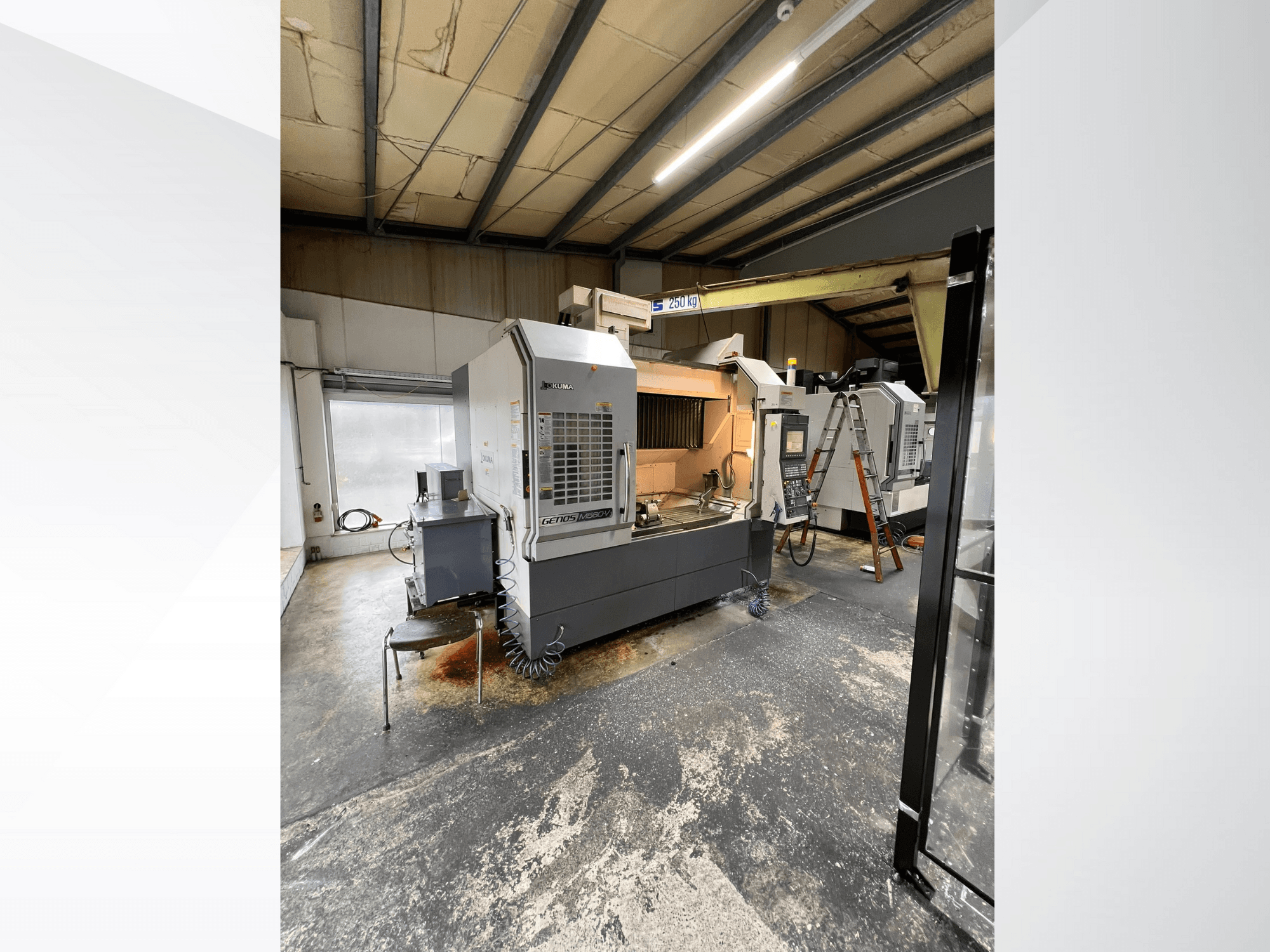 Станок с ЧПУ GRETOS 750 в мастерской, вид спереди, видна панель управления и рабочая зона с инструментами, на заднем плане видна лестница.