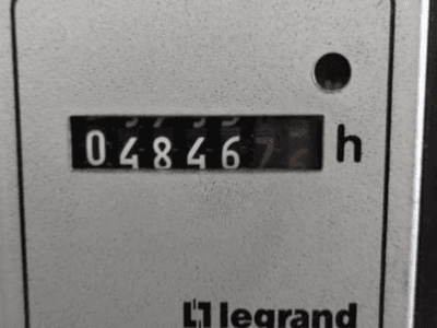 Счетчик моточасов Legrand с индикатором 048467.6, вид спереди с красным индикатором и черными цифрами на текстурированном светлом фоне.