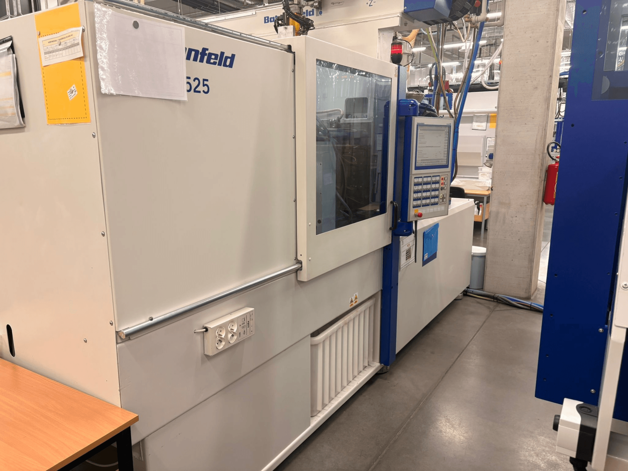 Станки Arburg, модель 620S, вид спереди, демонстрирующий панель управления и порты питания в заводских условиях.