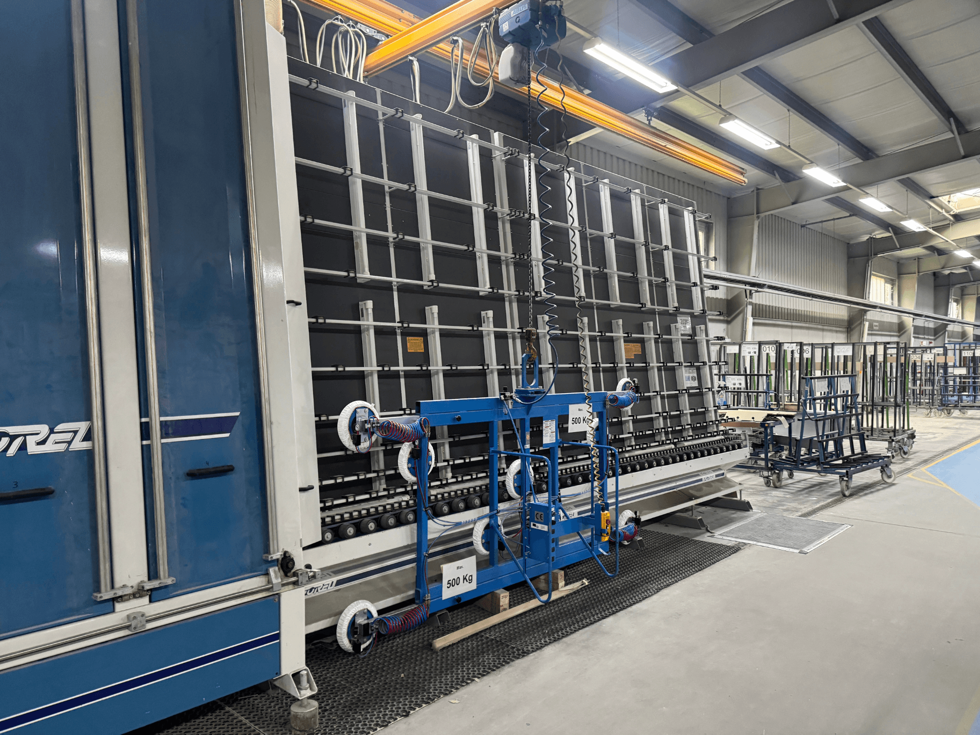 Промышленное оборудование Drel с большой рамой и подъемным механизмом, показанное с бокового ракурса в заводских условиях.