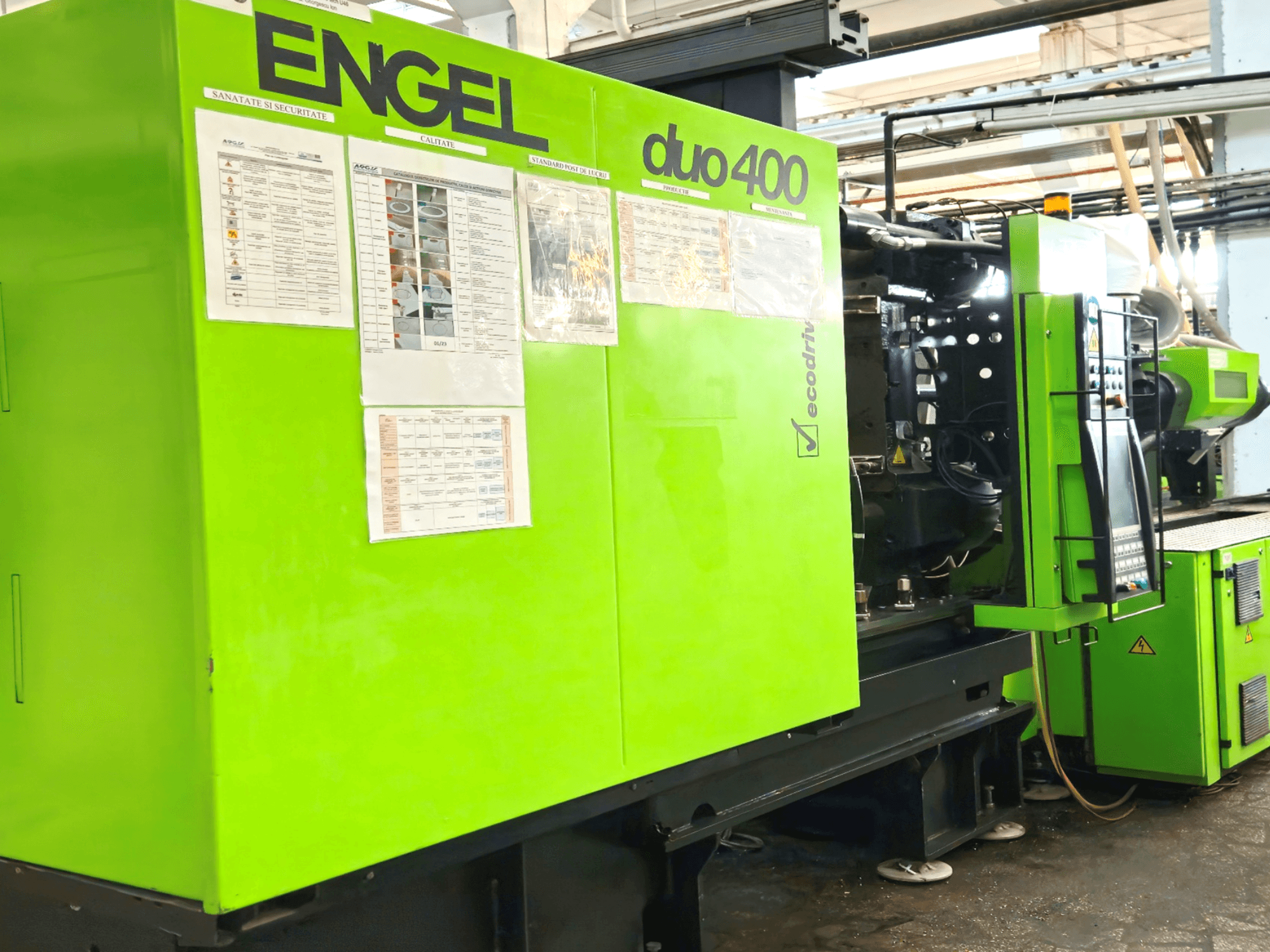 Зеленый термопластавтомат ENGEL duo 400, вид спереди, панель управления и документация по технике безопасности на внешней стороне.