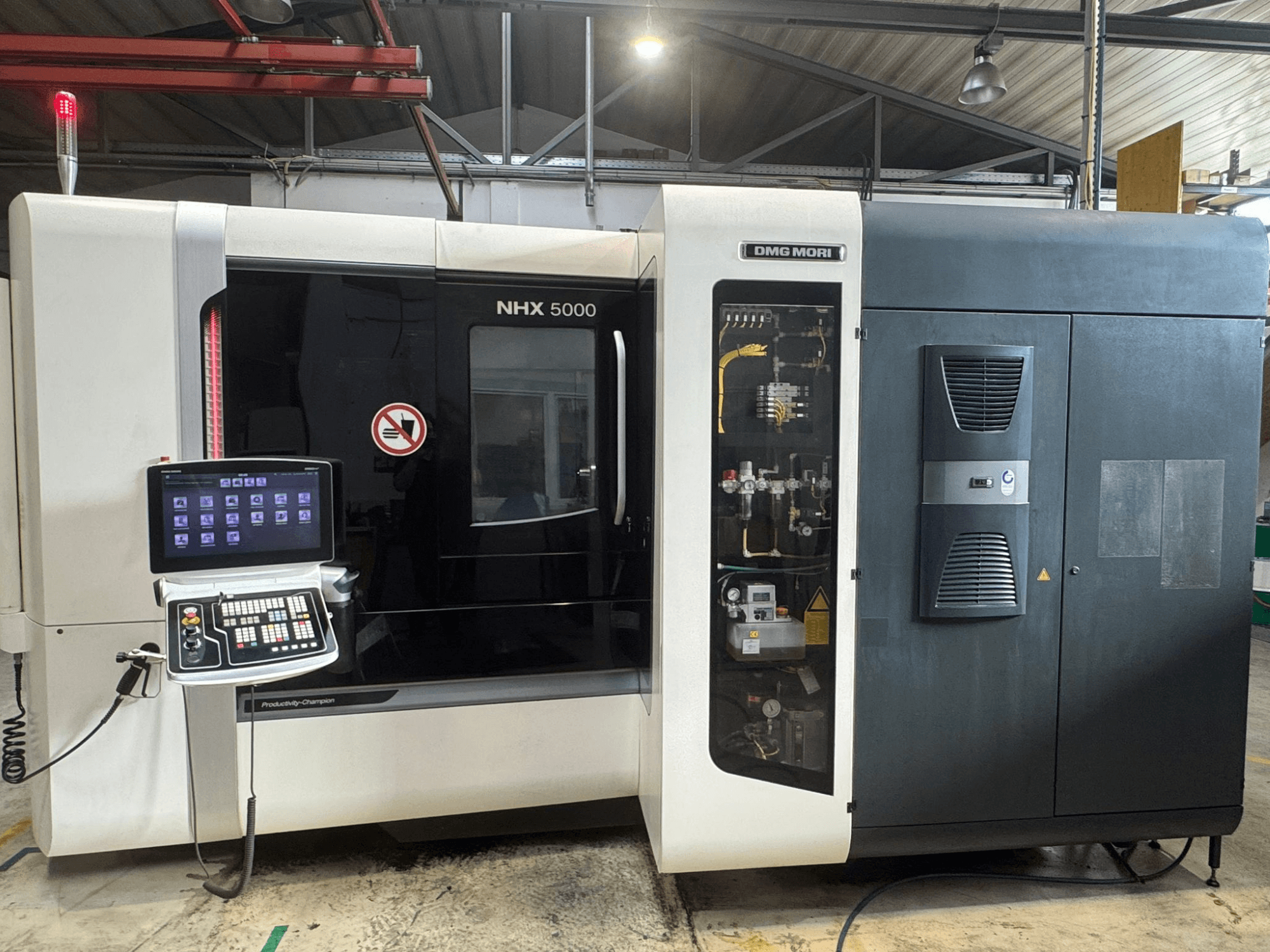 Вид спереди на горизонтальный обрабатывающий центр DMG MORI NHX 5000, демонстрирующий панель управления и детали станка.