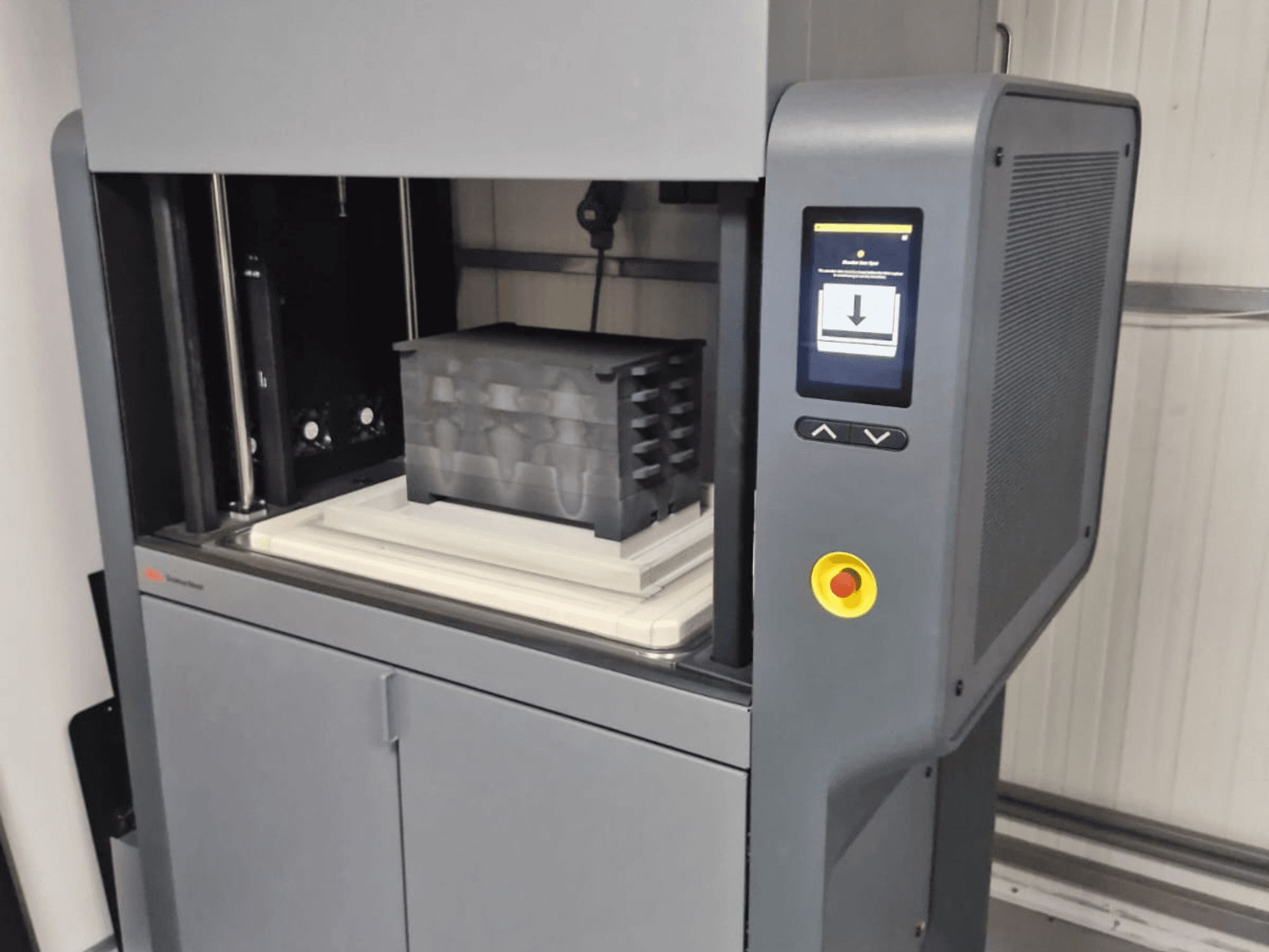 3D-принтер Metal Studio 2 от компании Desktop Metal, вид спереди, демонстрирующий панель управления и печатное ложе с черным контейнером.