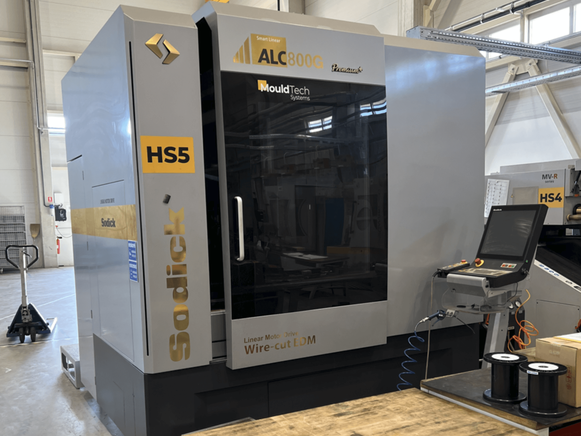 Проволочно-вырезной станок Sodick ALC800G Premium, вид спереди, демонстрирует панель управления и сложные детали конструкции.