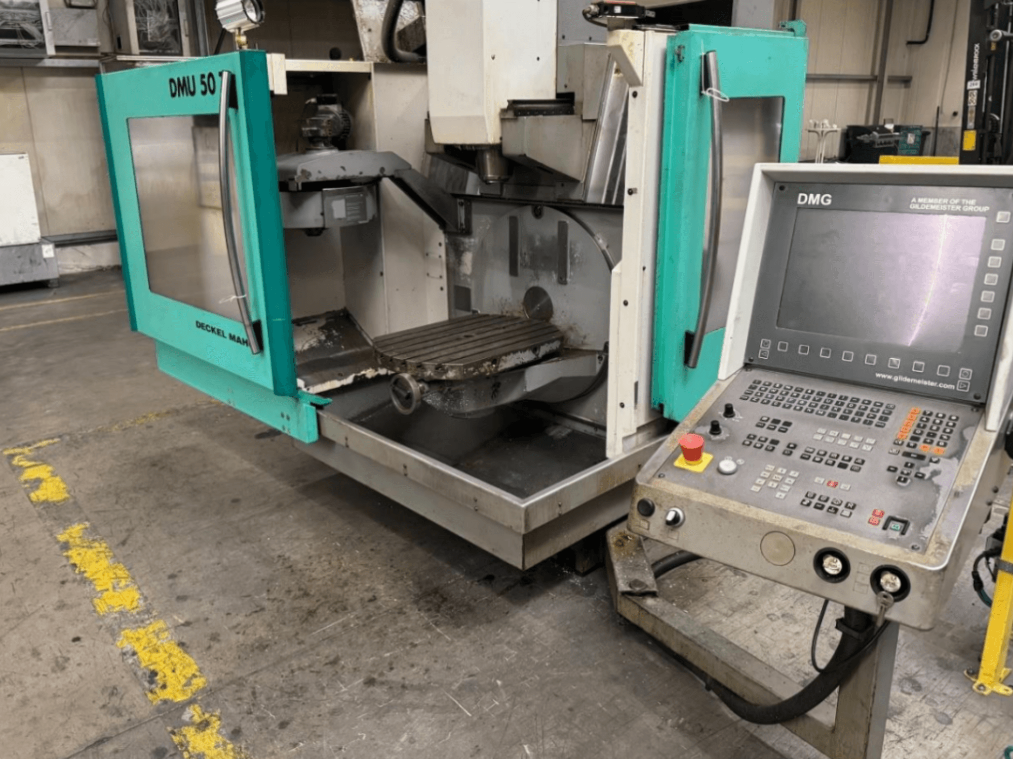 Фрезерный станок DMG DMU 50 с открытыми дверцами, показывающими внутреннее пространство и панель управления, вид спереди.